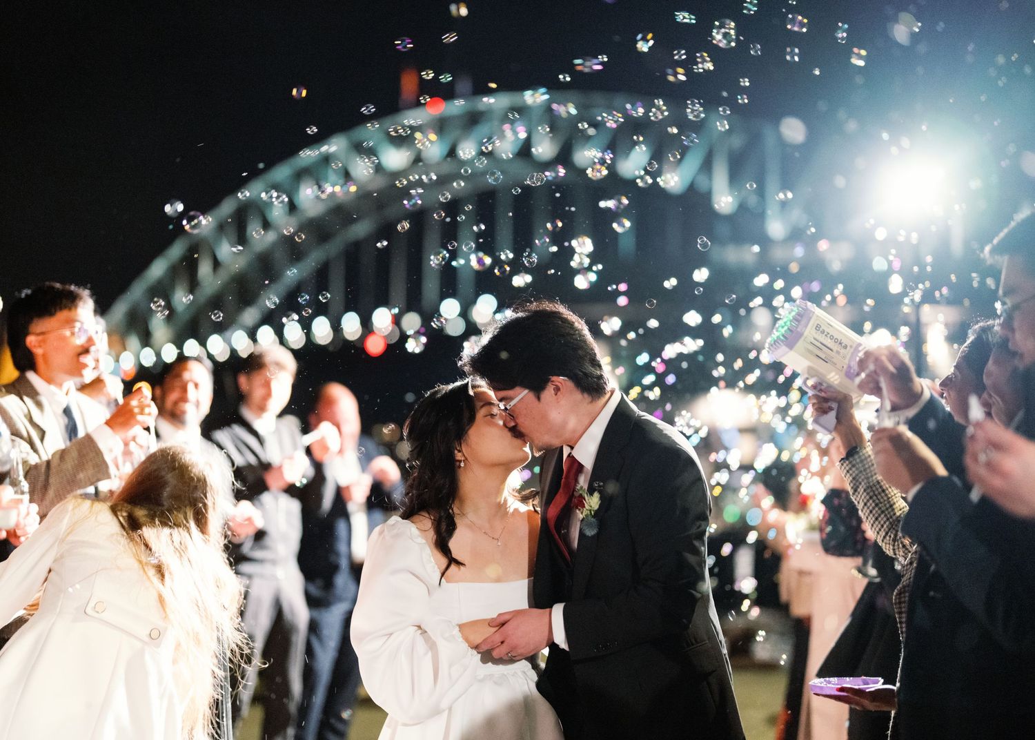 A wedding exit celebration with bubbles and sparklers creating a magical nighttime atmosphere.