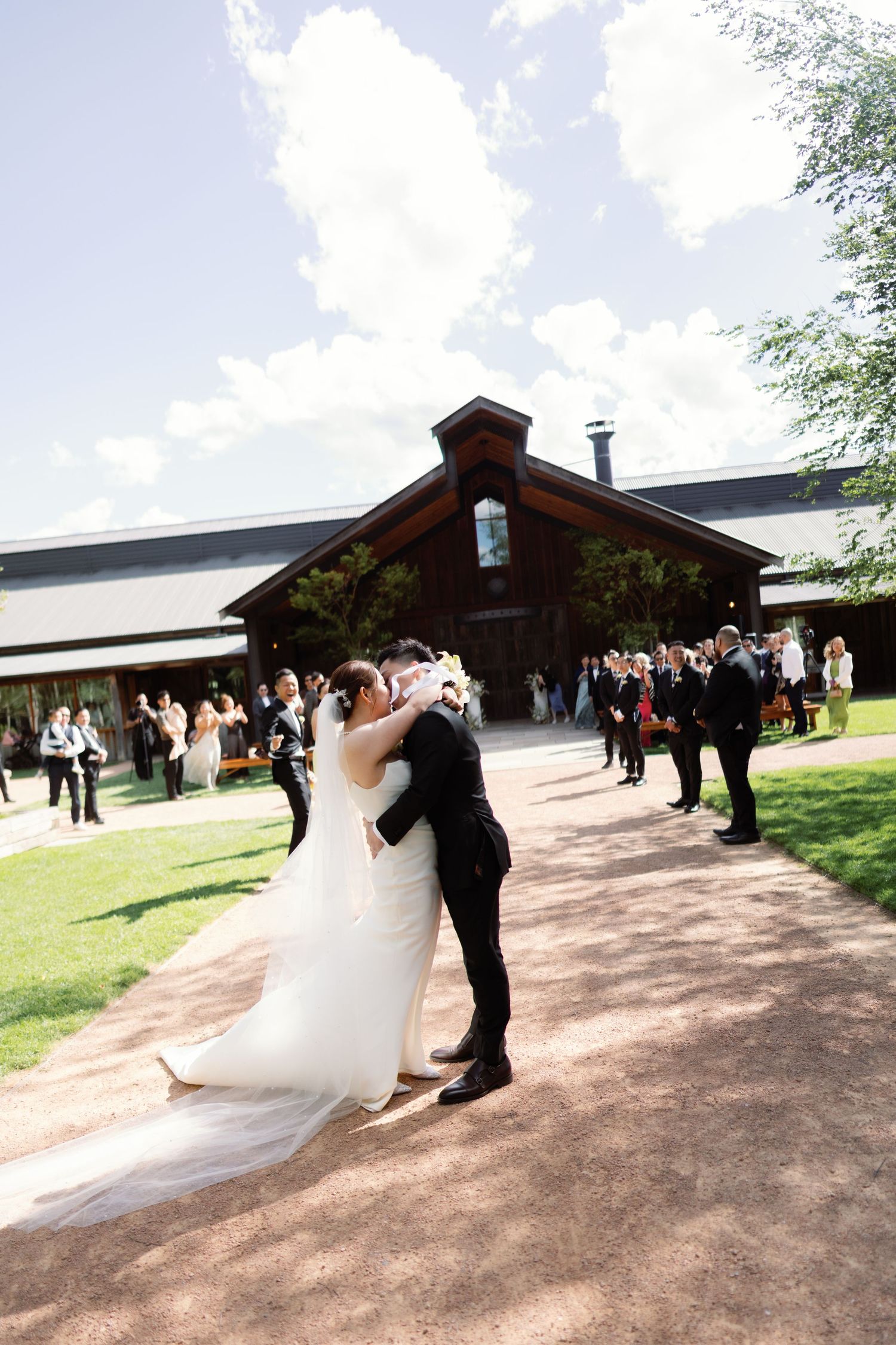 Wedding ceremony taking place at a modern rustic venue with guests gathered outdoors.