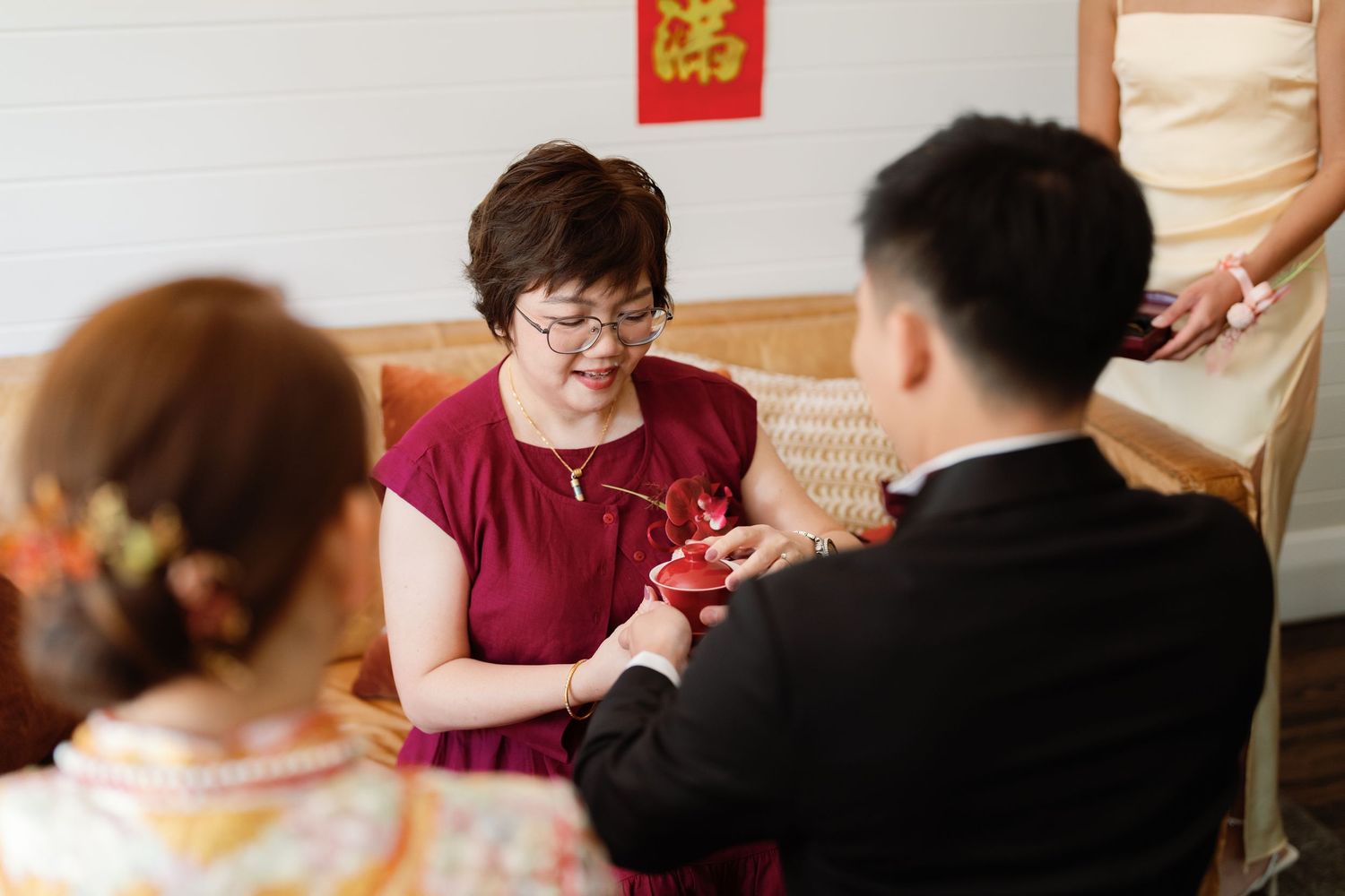 Wedding guests participate in traditional tea ceremony rituals indoors.