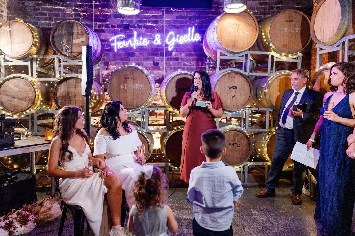 Wedding celebration in rustic venue with purple lighting and wine barrel decor.