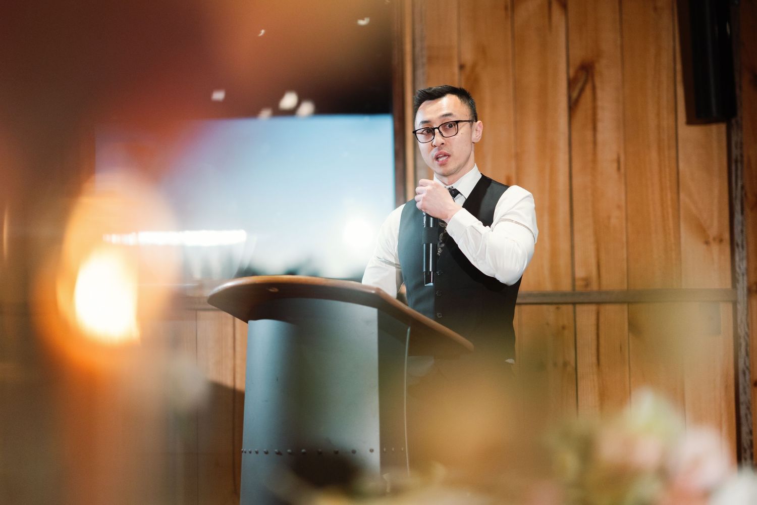 A wedding reception venue with warm lighting and wooden panel walls creates an intimate atmosphere.