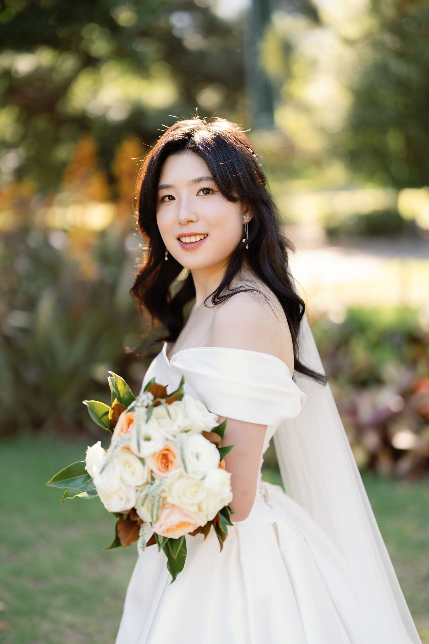 Elegant bridal portraits in a garden setting with peach and white floral bouquet.