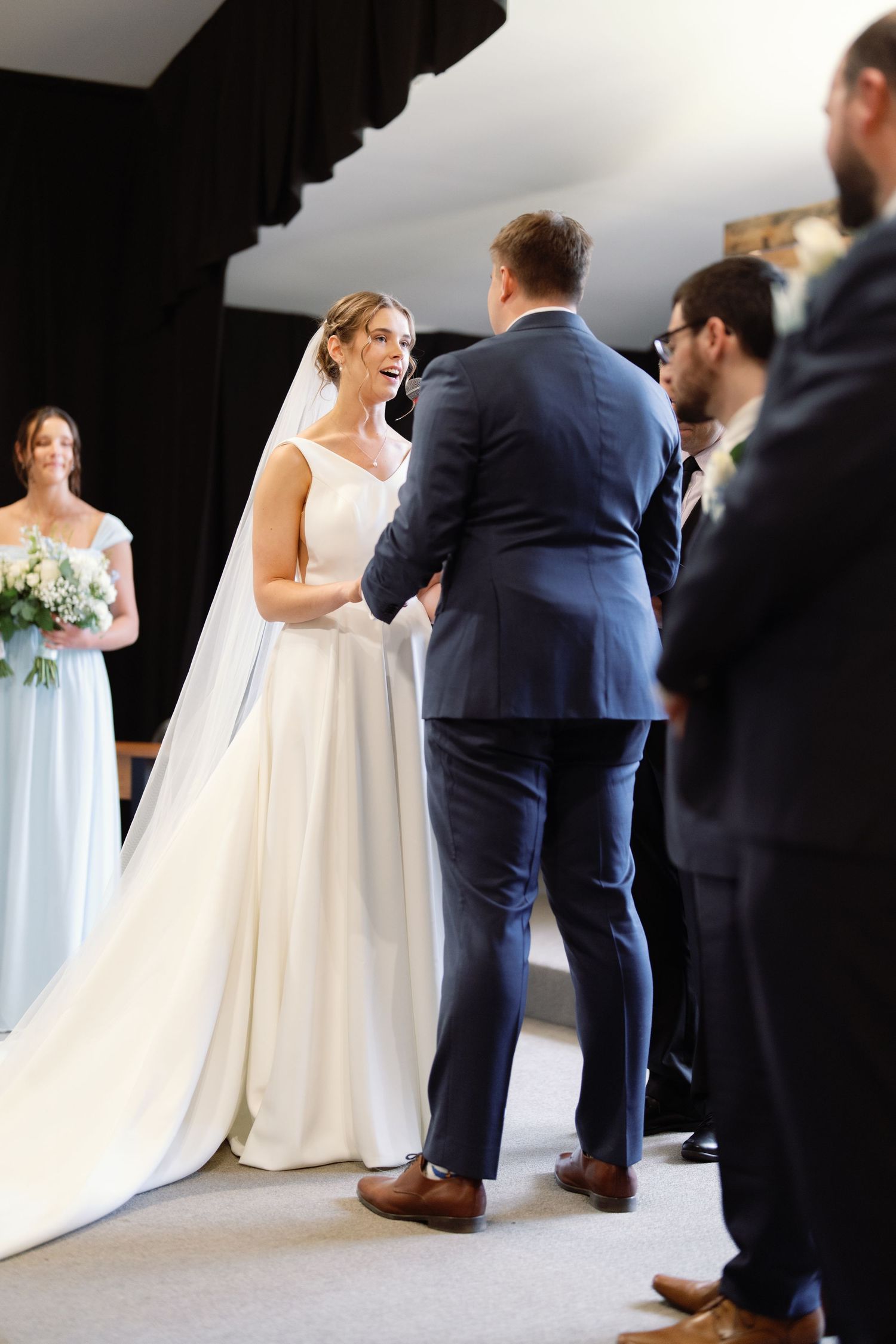 Wedding party lineup with groomsmen in navy suits and bridesmaids in light blue dresses.