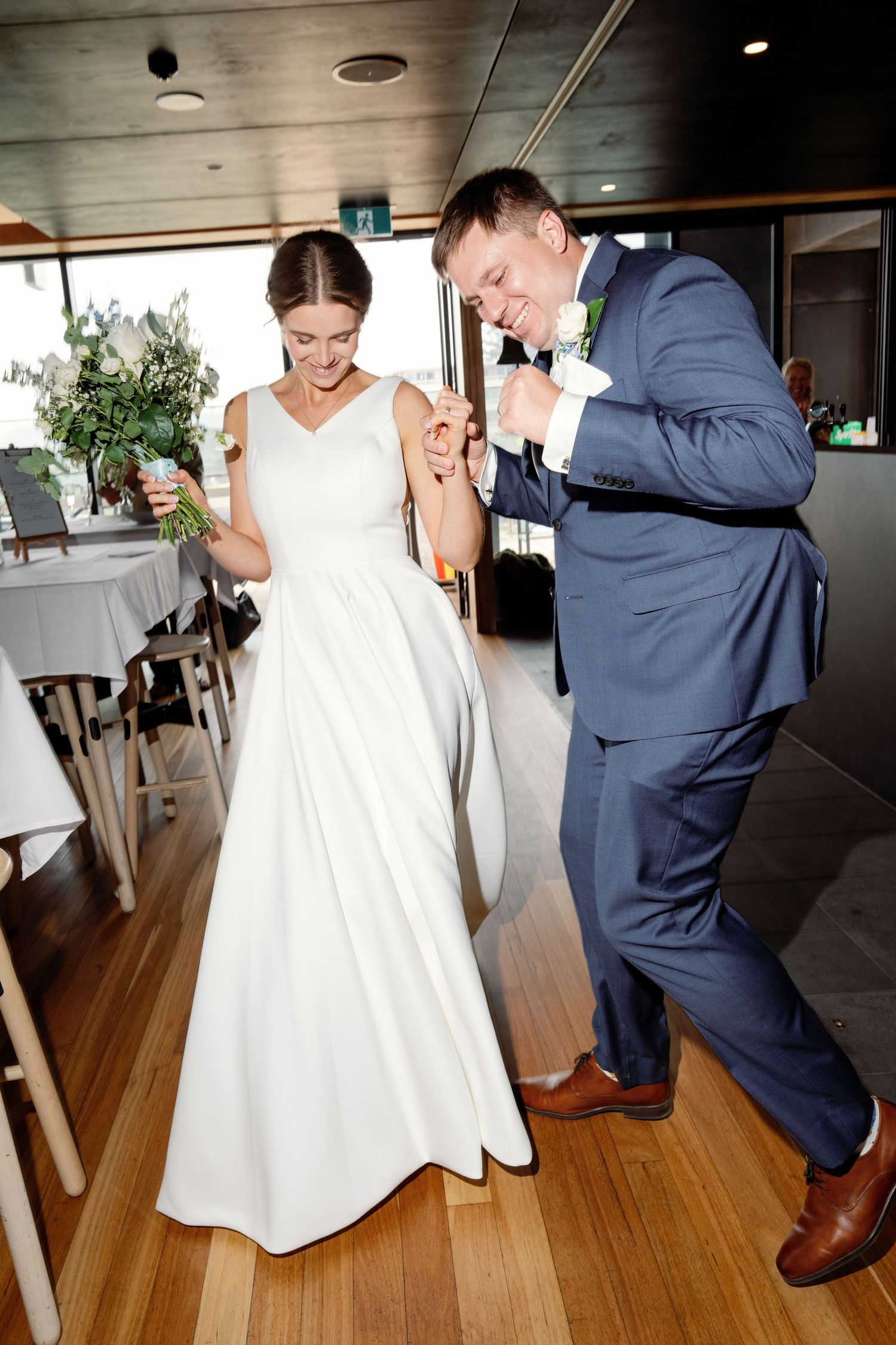 Playful dance moves captured on a wooden floor during a wedding celebration.
