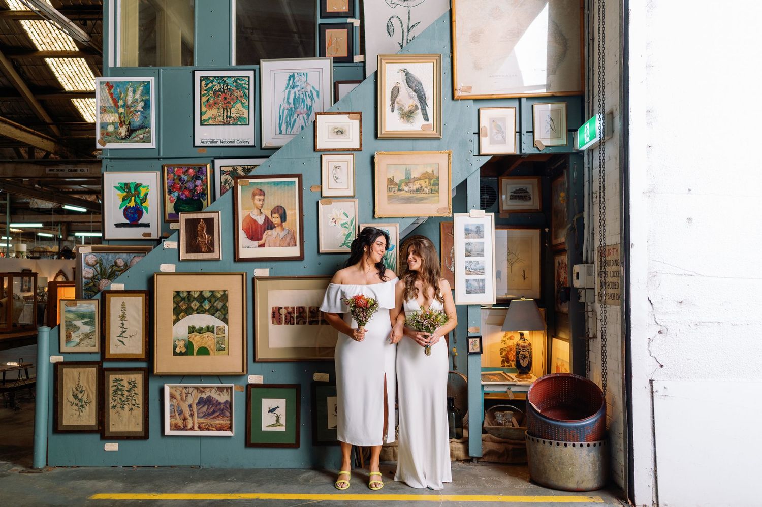 Art gallery interior with teal walls displaying various framed artwork and photographs.