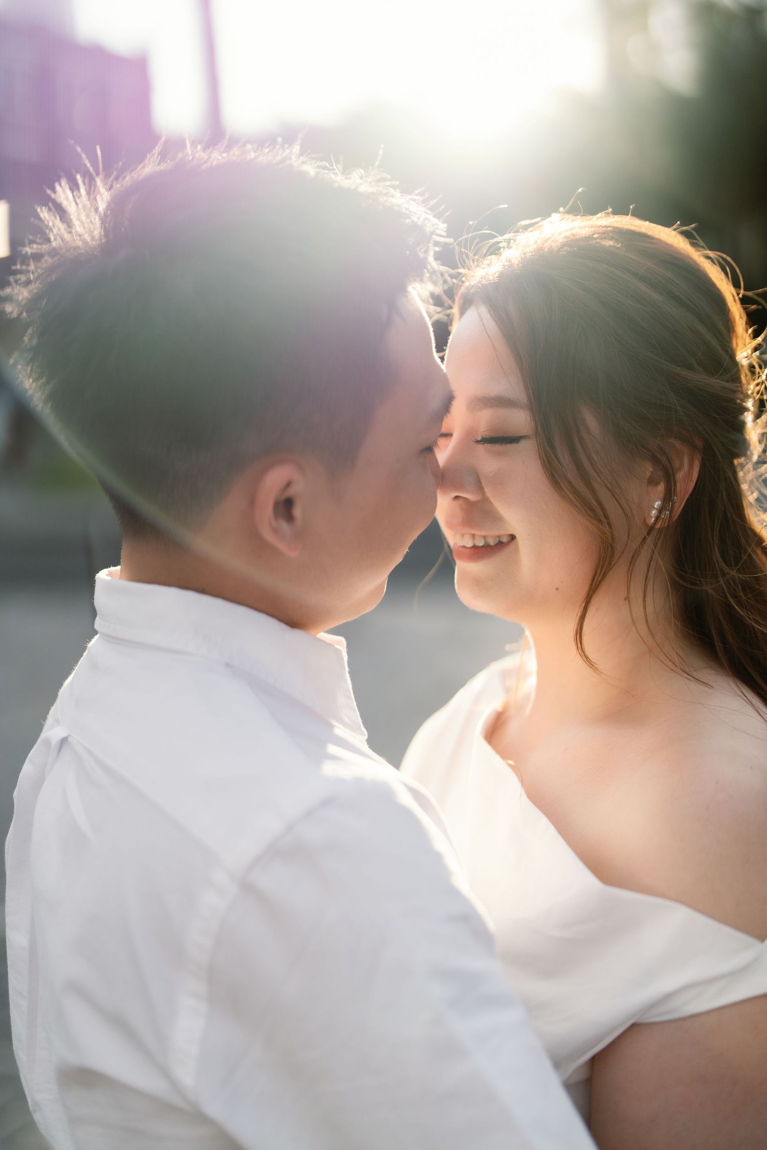 A romantic couple shares an intimate moment in golden sunlight, with soft backlighting creating a dreamy atmosphere.