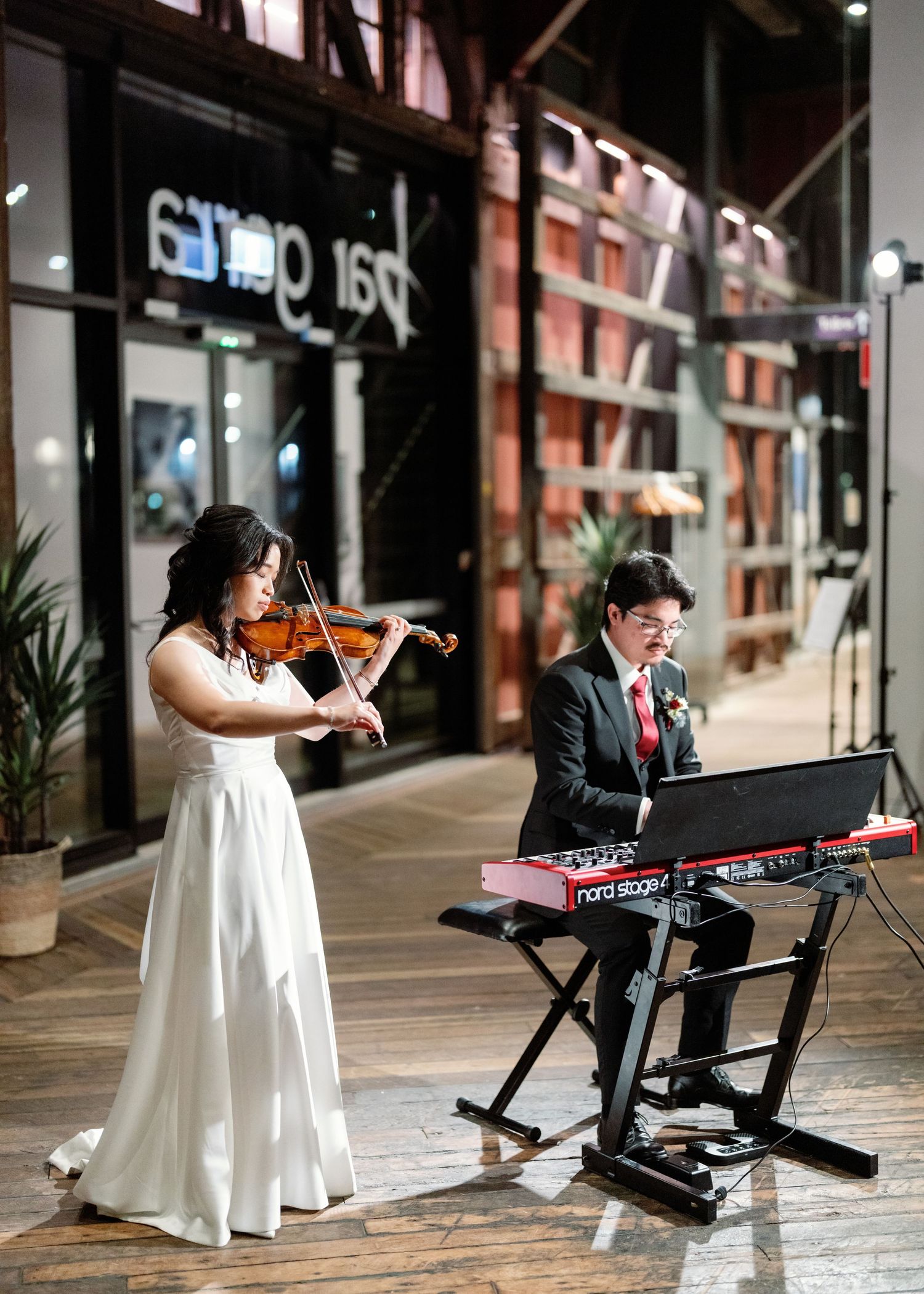 Musicians performing with violin and keyboard at an indoor venue.