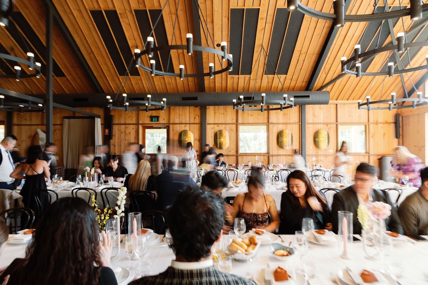 Wedding reception venue with wooden ceiling beams and tables set for dining.