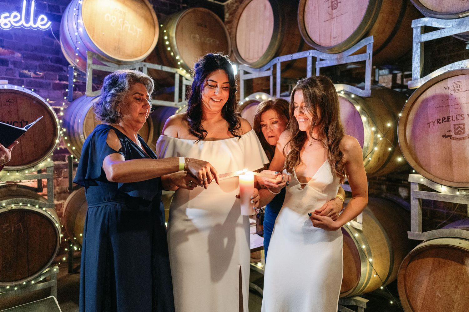 Group celebrating in a wine cellar with wooden barrels and warm lighting creating a festive ambiance.