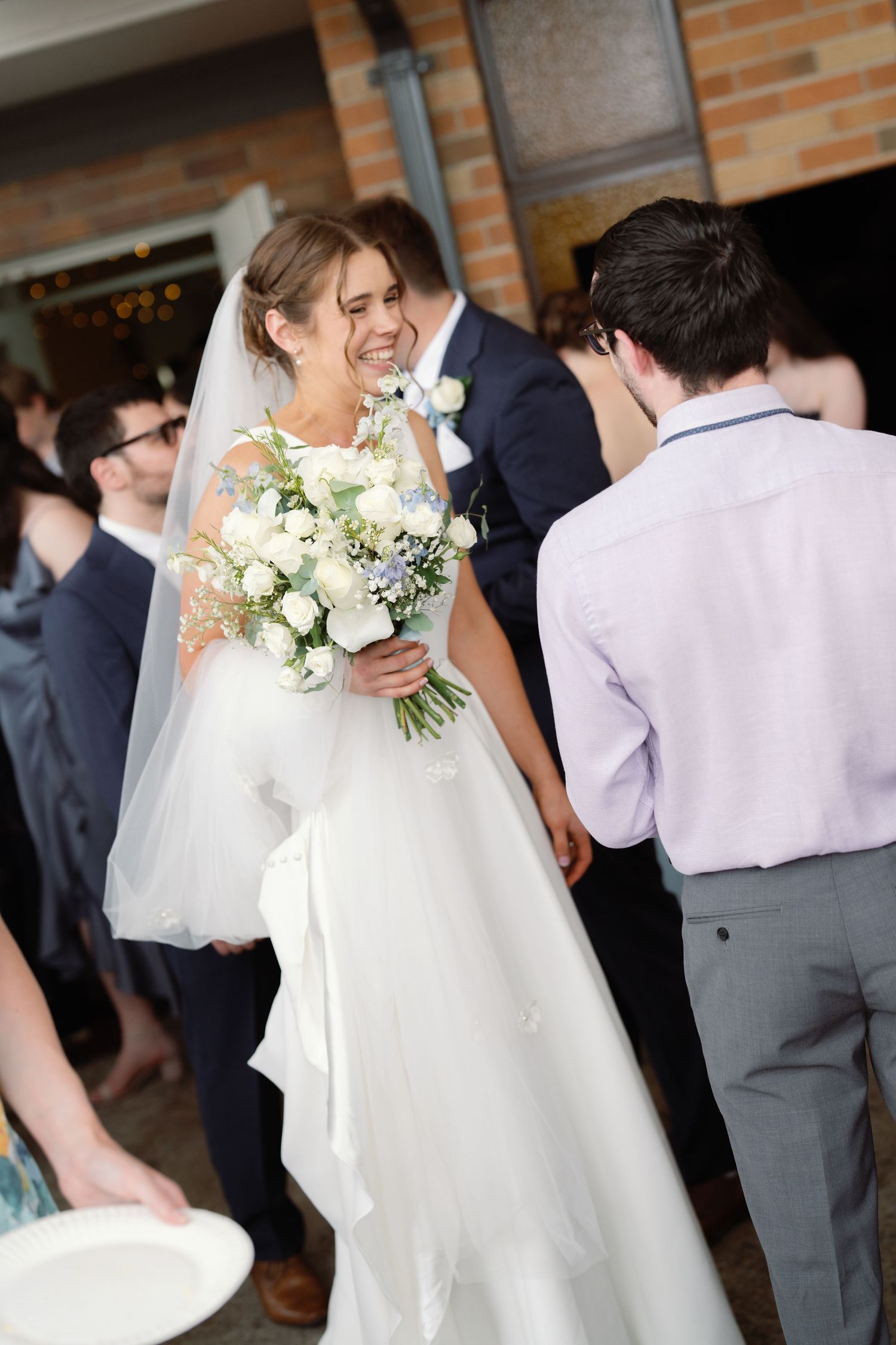 Wedding party members in formal attire gather in a brick-walled venue.