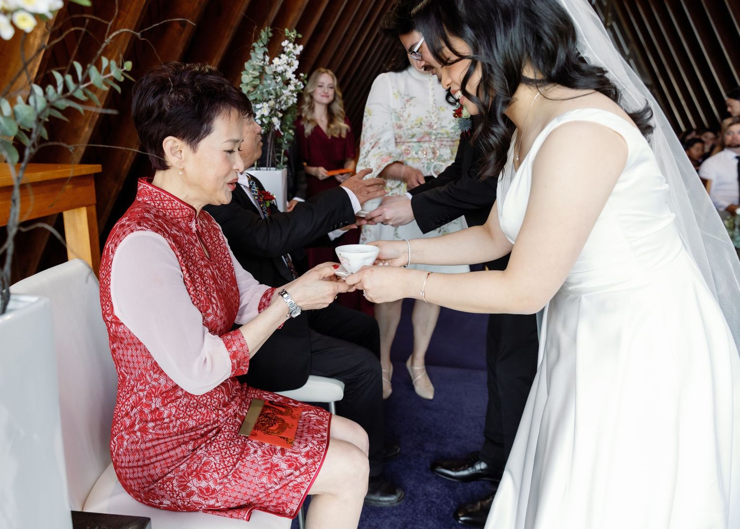Wedding guests gather around tables during reception celebration.