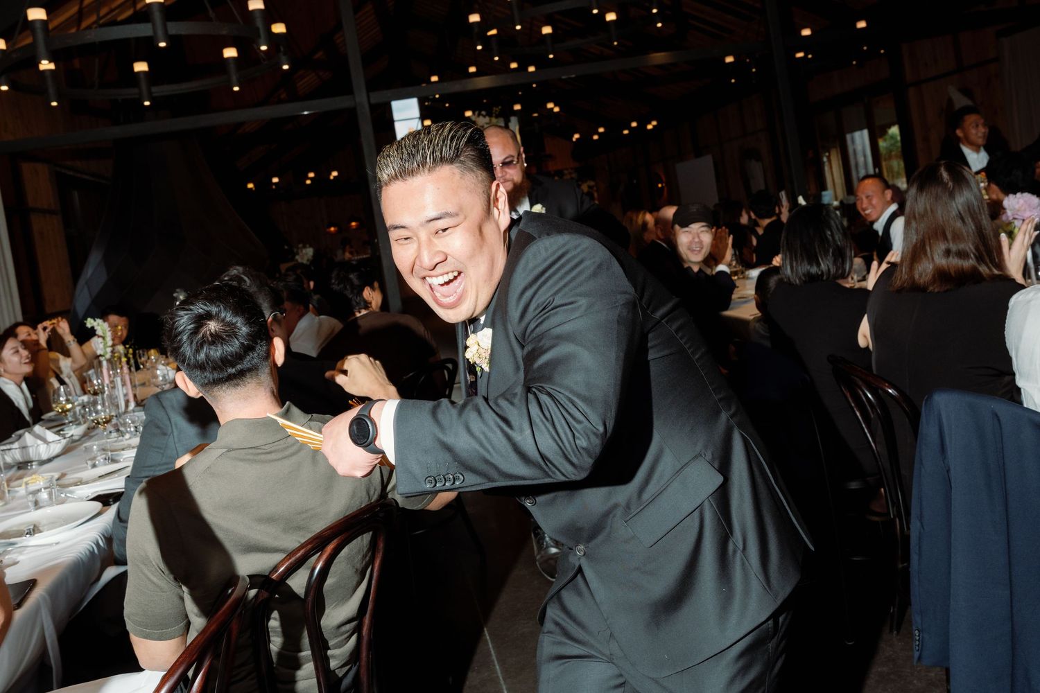 A guest in a dark suit shows excitement during the wedding reception.