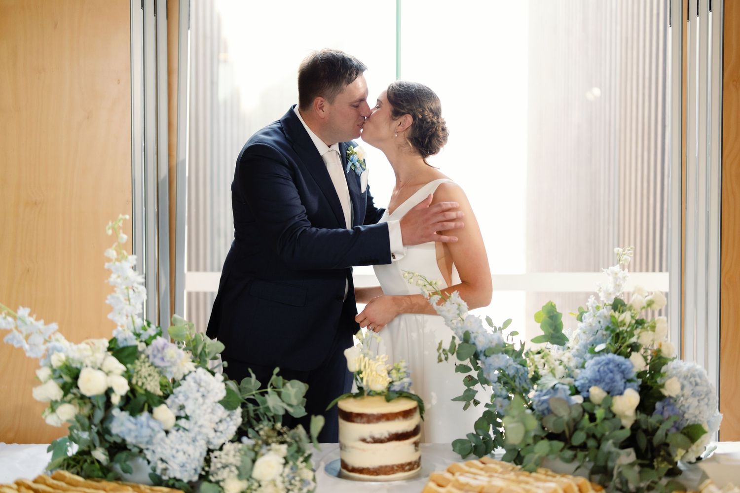 Elegant wedding reception setup with white floral arrangements and a rustic naked cake.