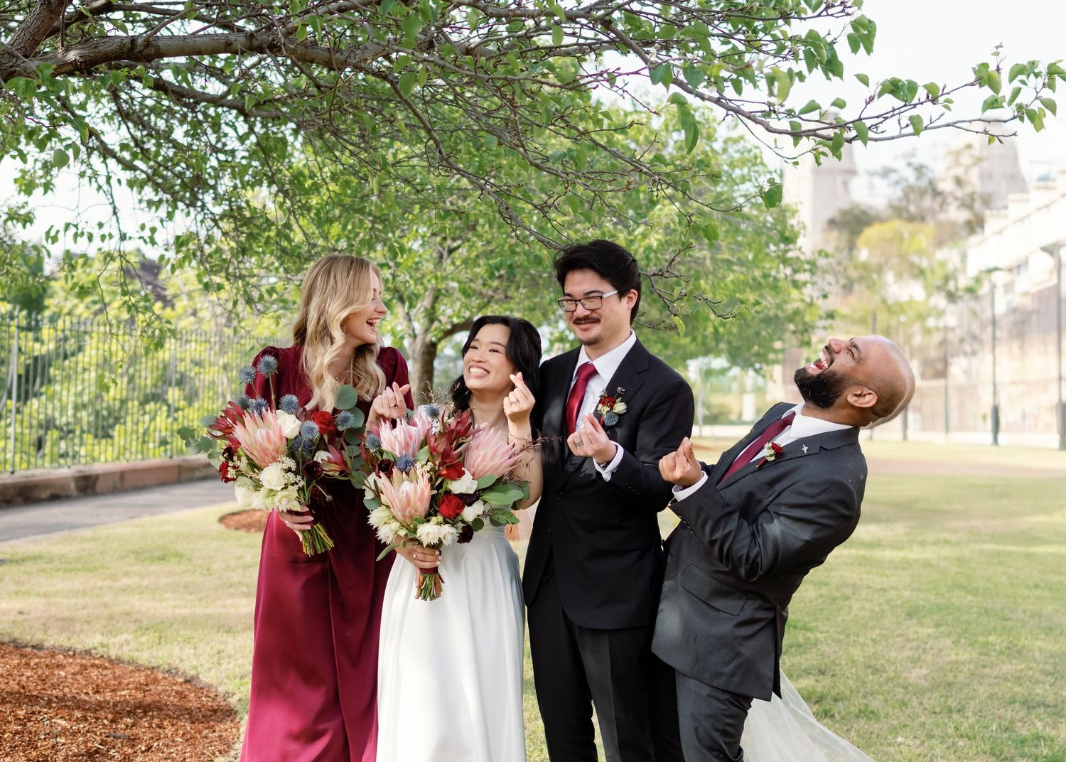 Wedding party members pose together outdoors during autumn with burgundy and white color scheme and natural foliage.