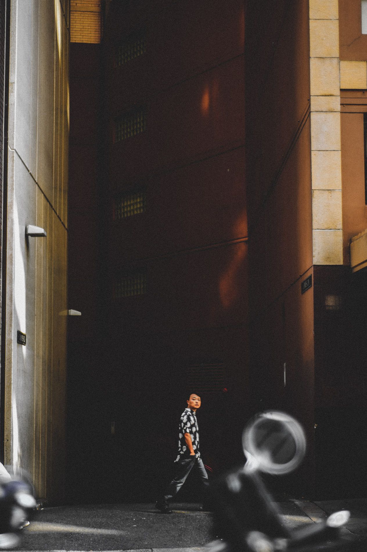 Silhouette walking through dramatic urban architecture with strong lighting and shadows.