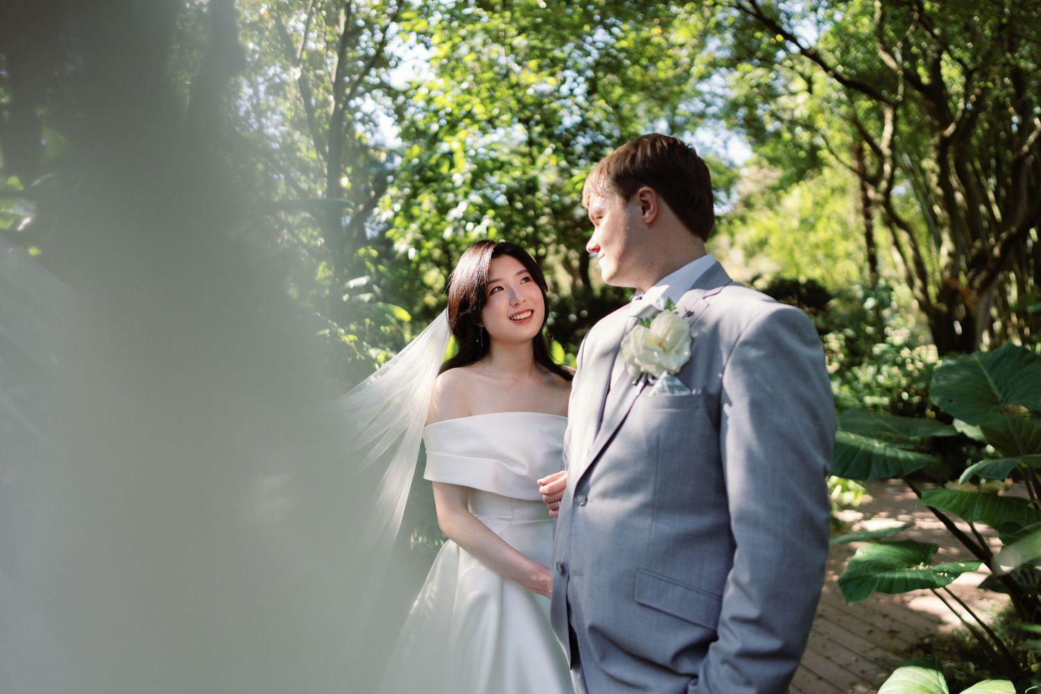 Couple shares romantic moments in a sunlit garden setting during their wedding photoshoot.