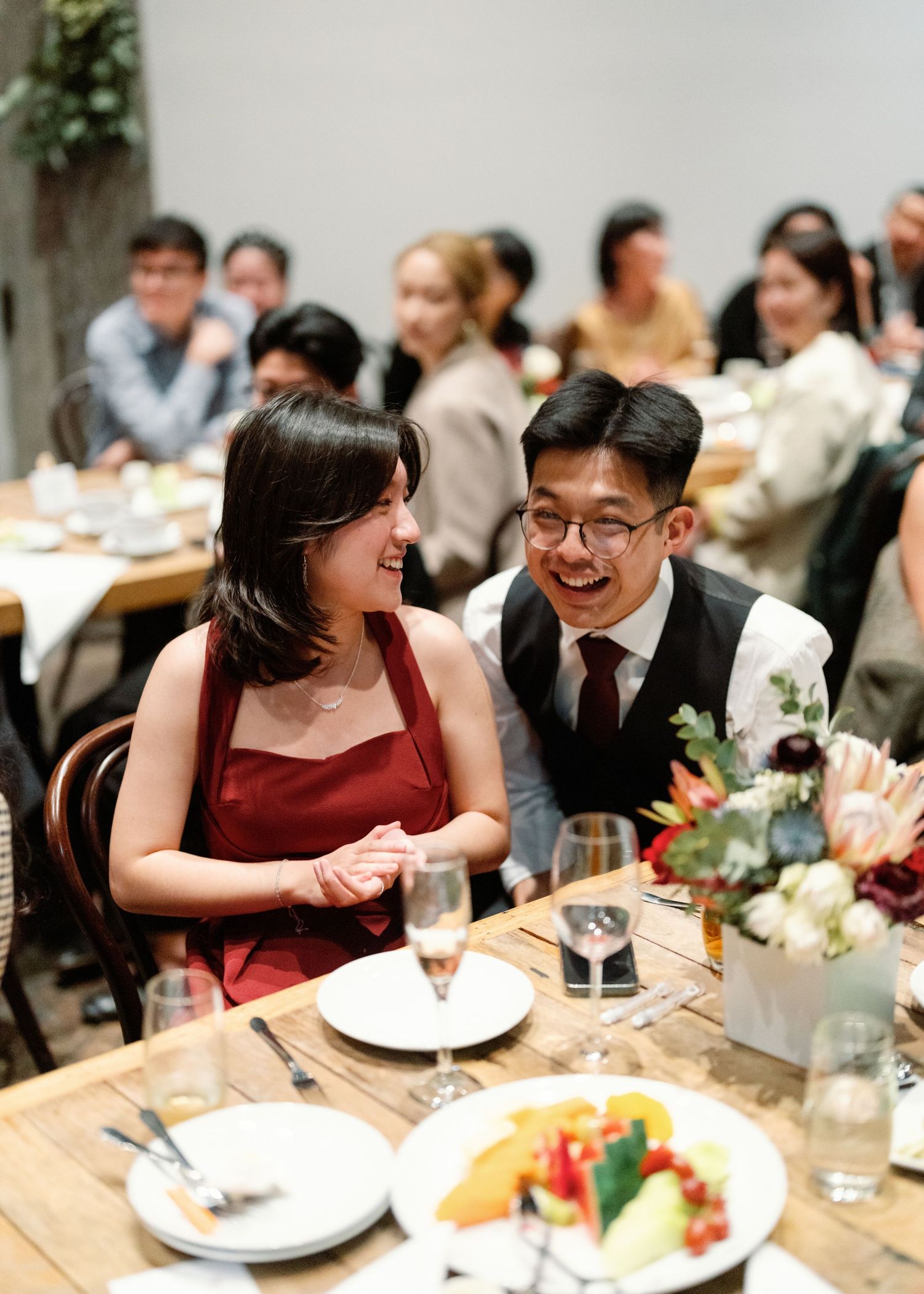 Wedding reception dinner with guests seated at rustic tables with elegant place settings.