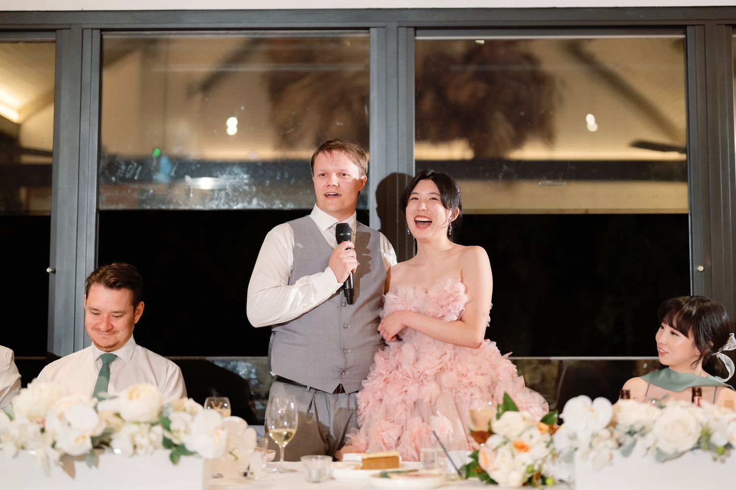Wedding reception venue with floor-to-ceiling windows and elegant table settings.