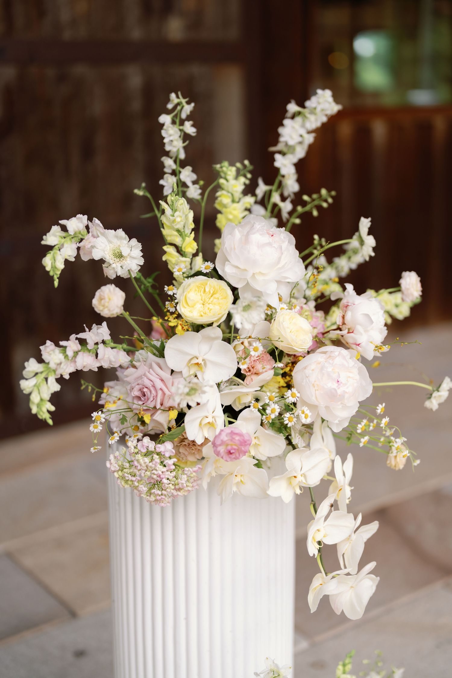 Elegant floral centerpiece with pink and white roses in a white ribbed vase on a light surface.