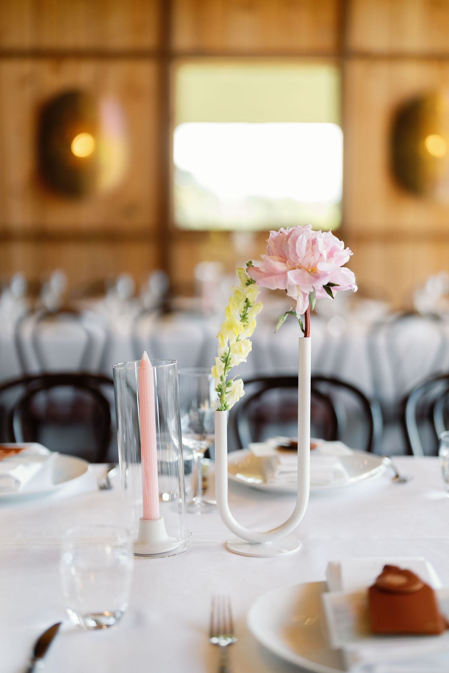 Elegant table settings with pink flowers and white candles for a wedding reception.
