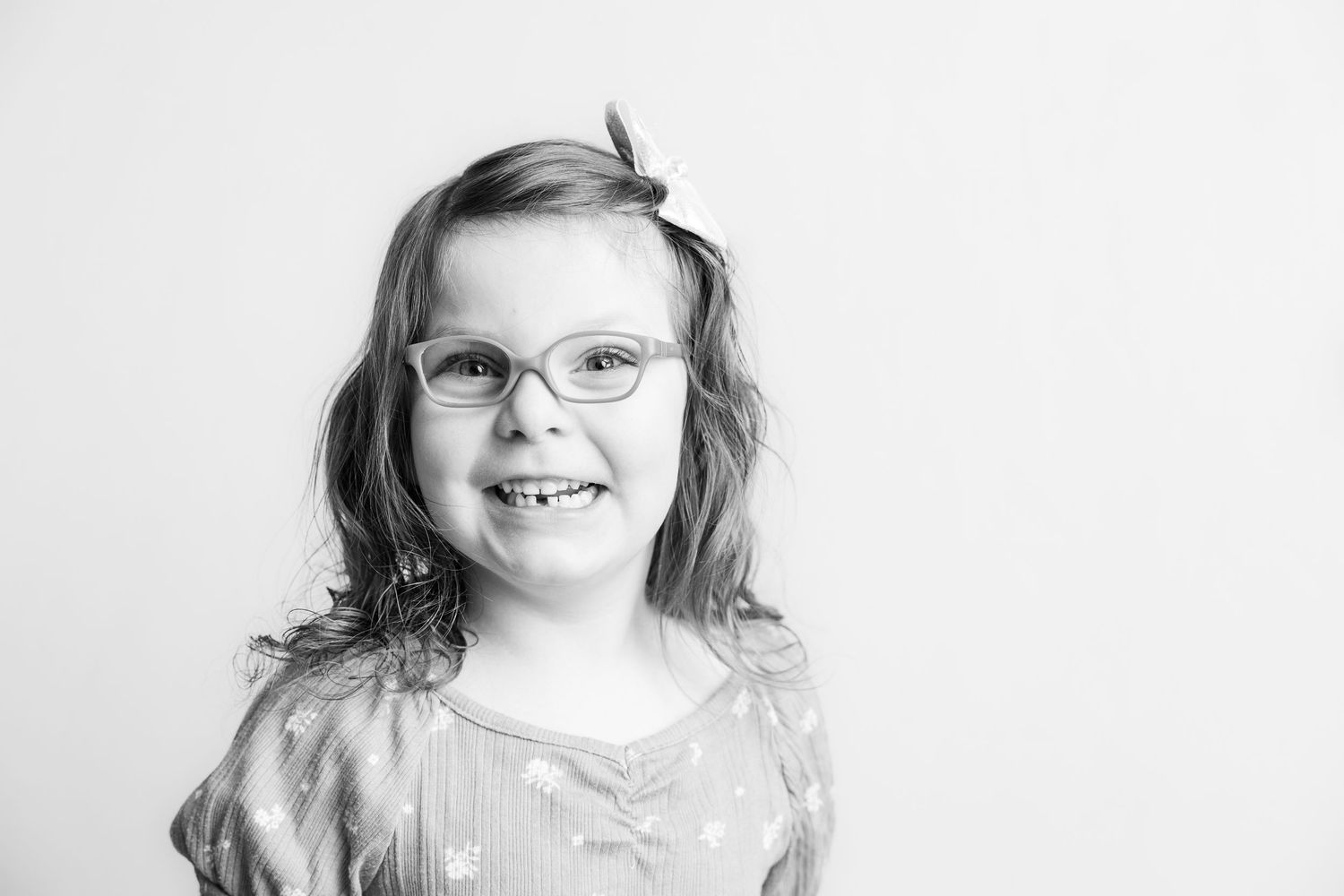 Black and white portrait series showing people wearing glasses and looking happy with bright smiles.