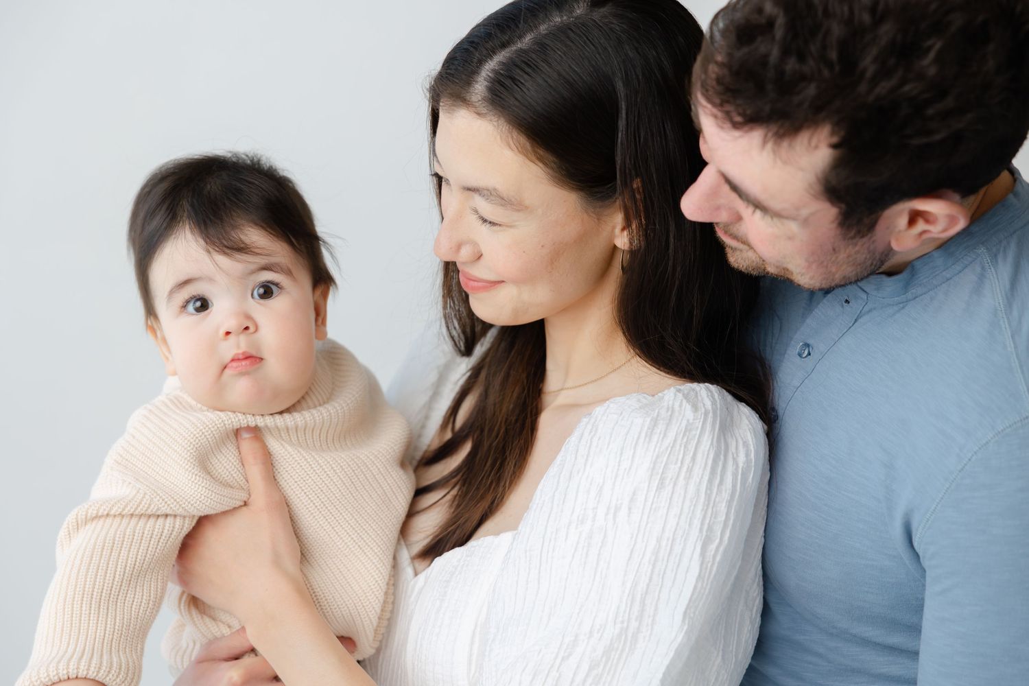 A series of intimate family portraits showing tender moments between parents and baby in soft neutral tones.