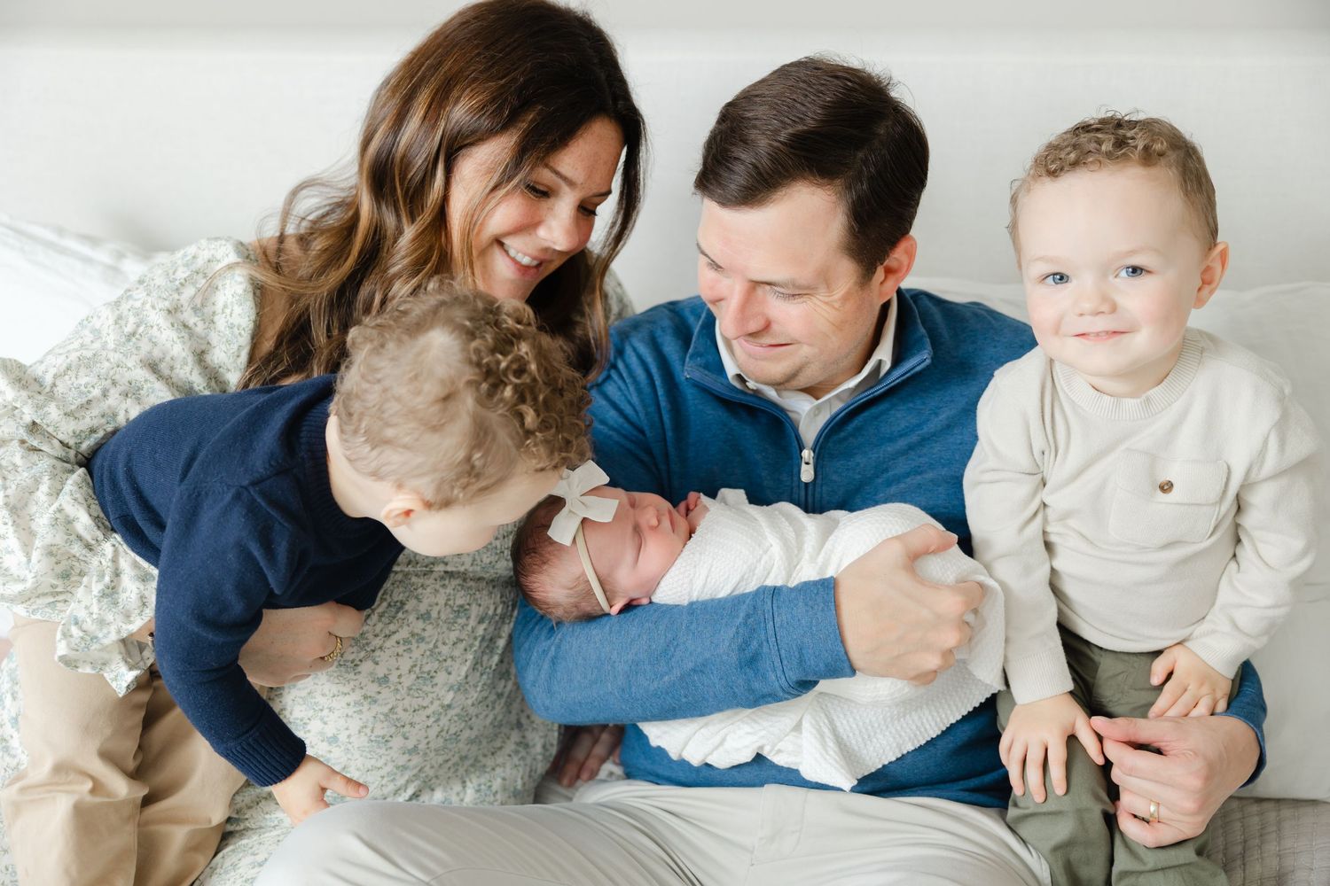 A family in coordinated white and blue outfits shares tender moments together during a photo session.