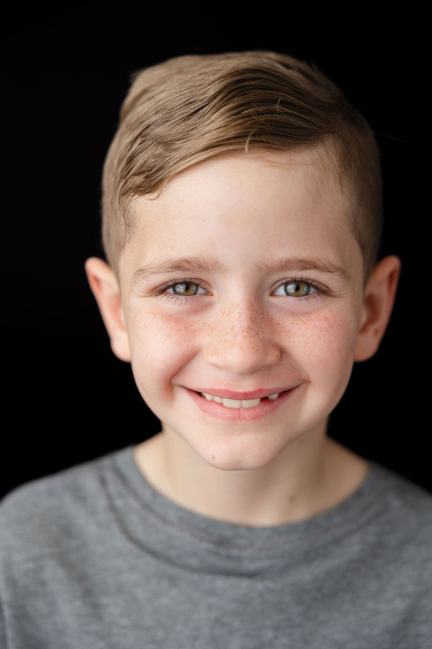Studio portrait series against dark background showing natural smiles wearing grey casual top.