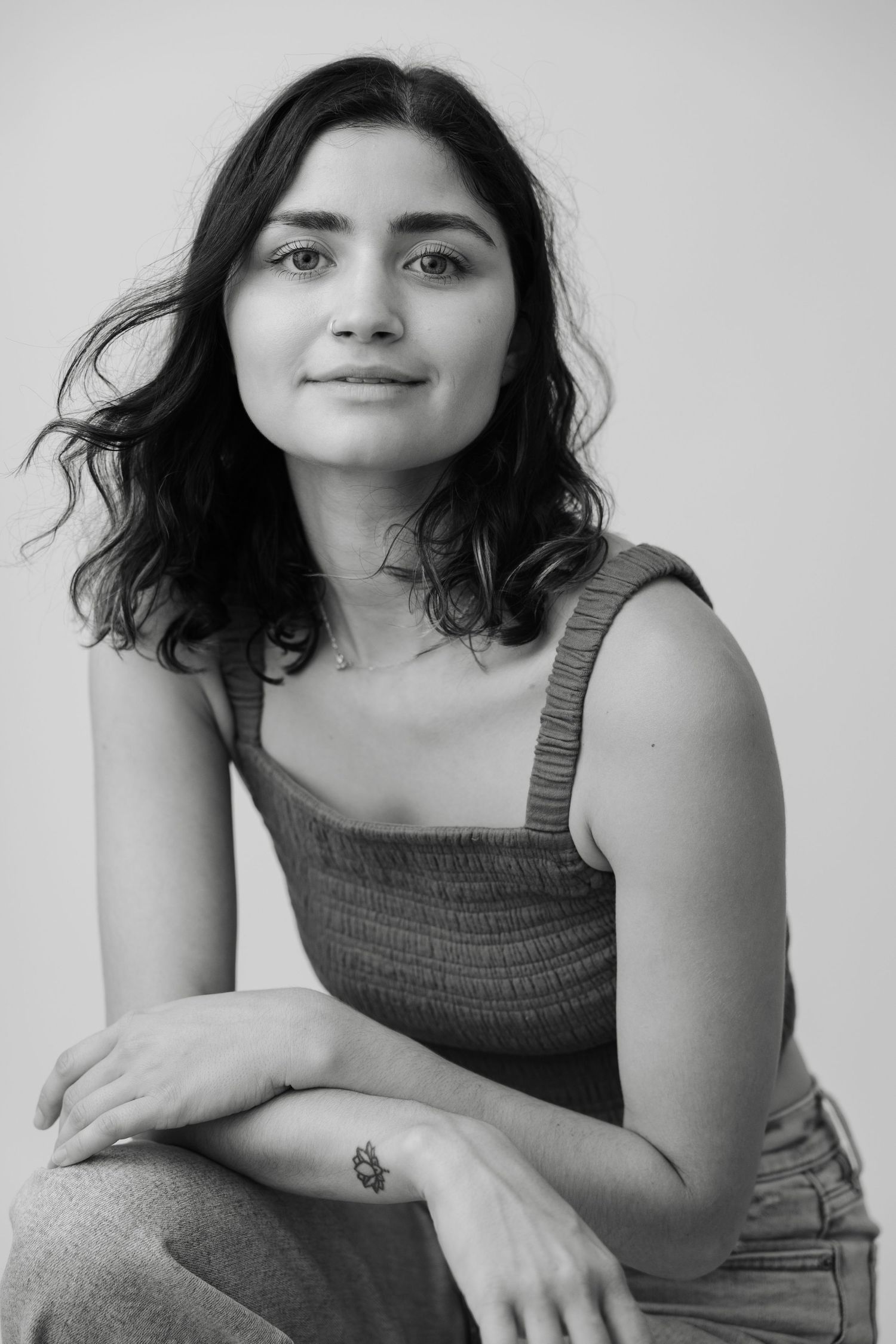Series of black and white portraits showing someone in a tank top against a light background expressing different emotions.