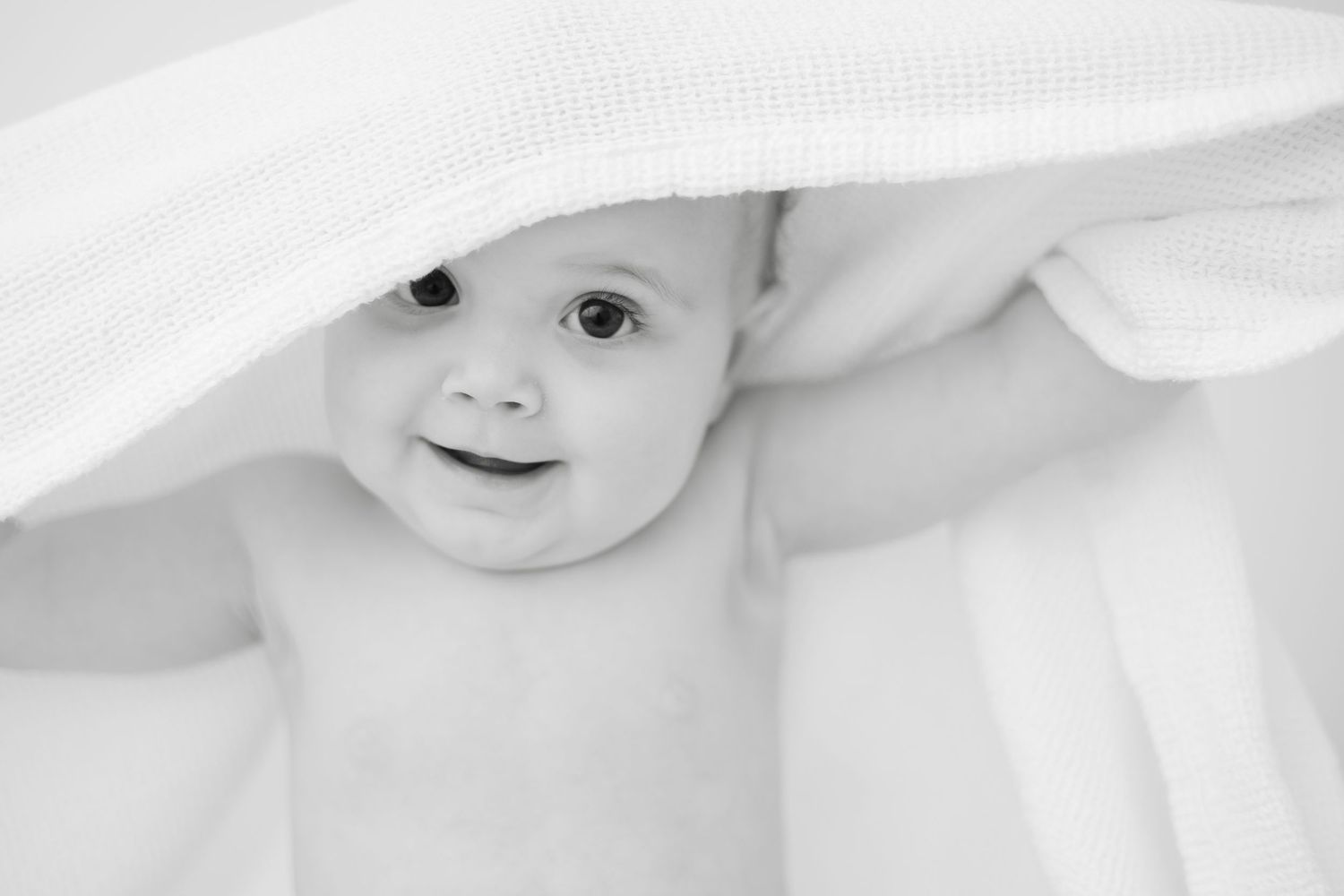 A series of black and white close-up portraits of a baby showing different expressions and angles.