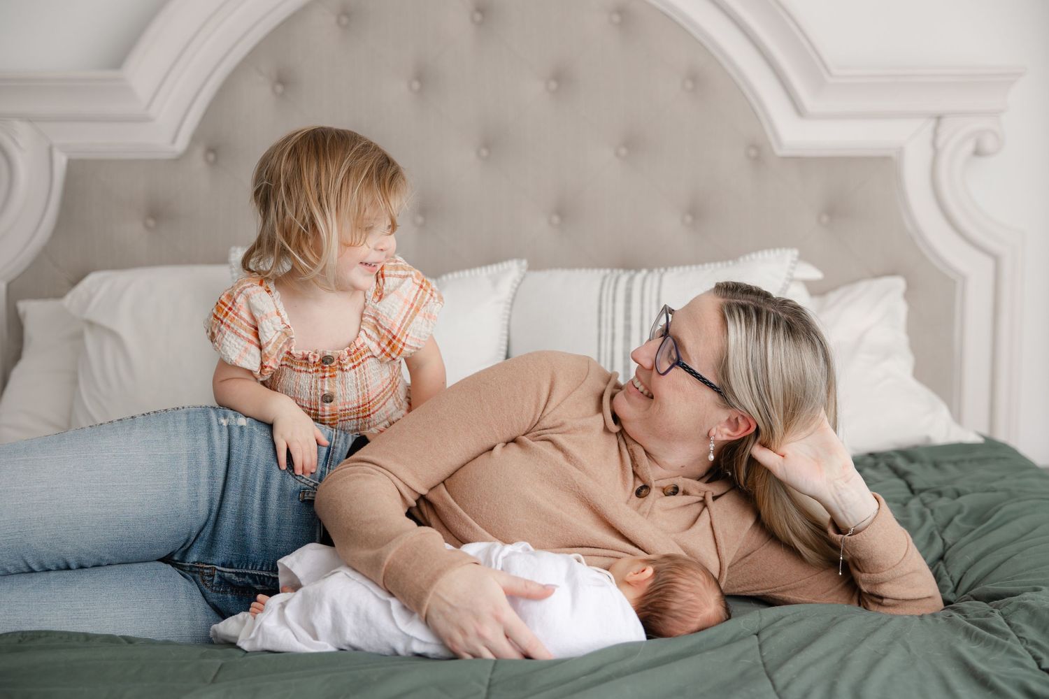 A tender family moment shared on a plush bed with comfortable pillows and neutral colored bedding.
