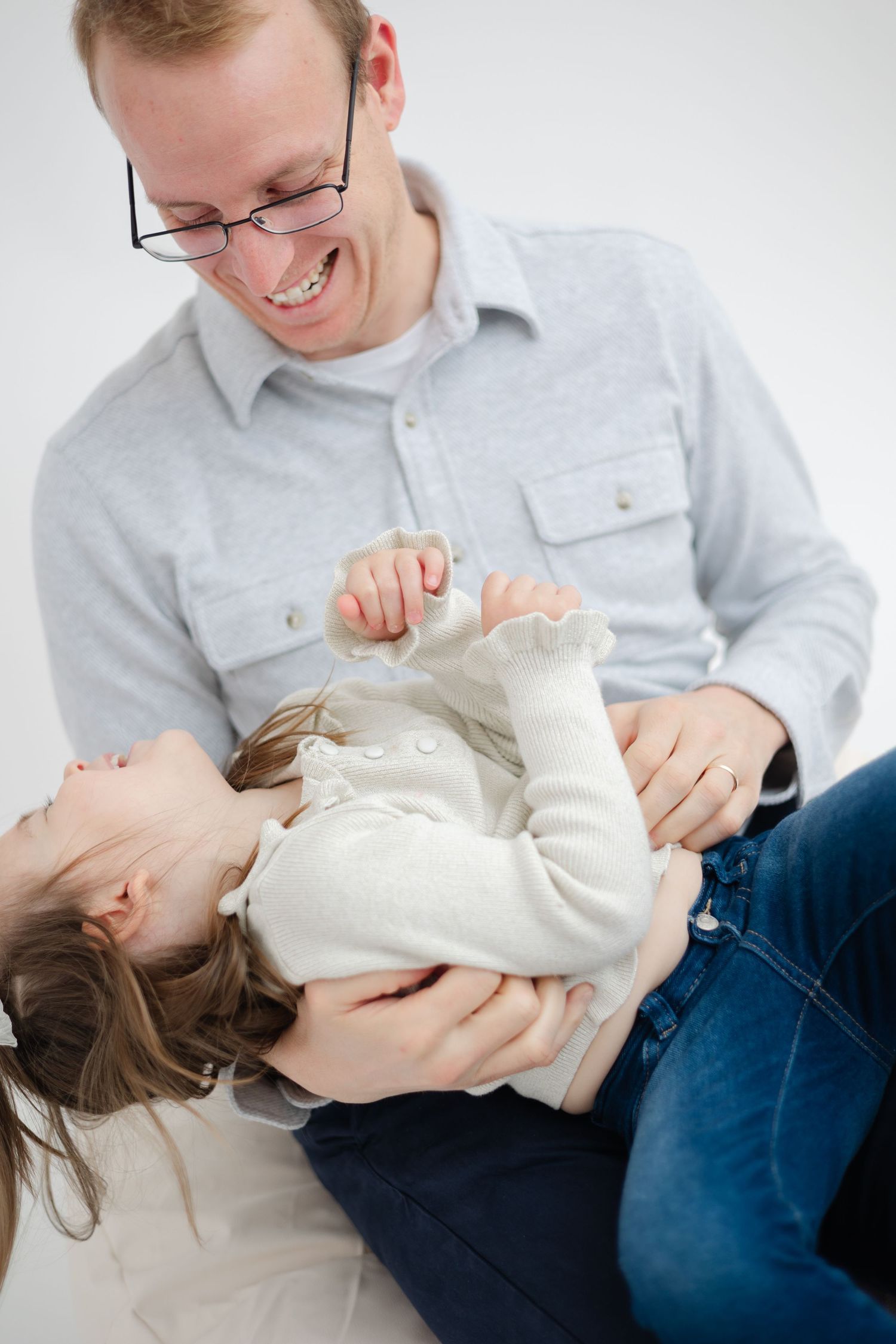 Sequence of playful moments showing parent and child in white and blue clothing on light background.
