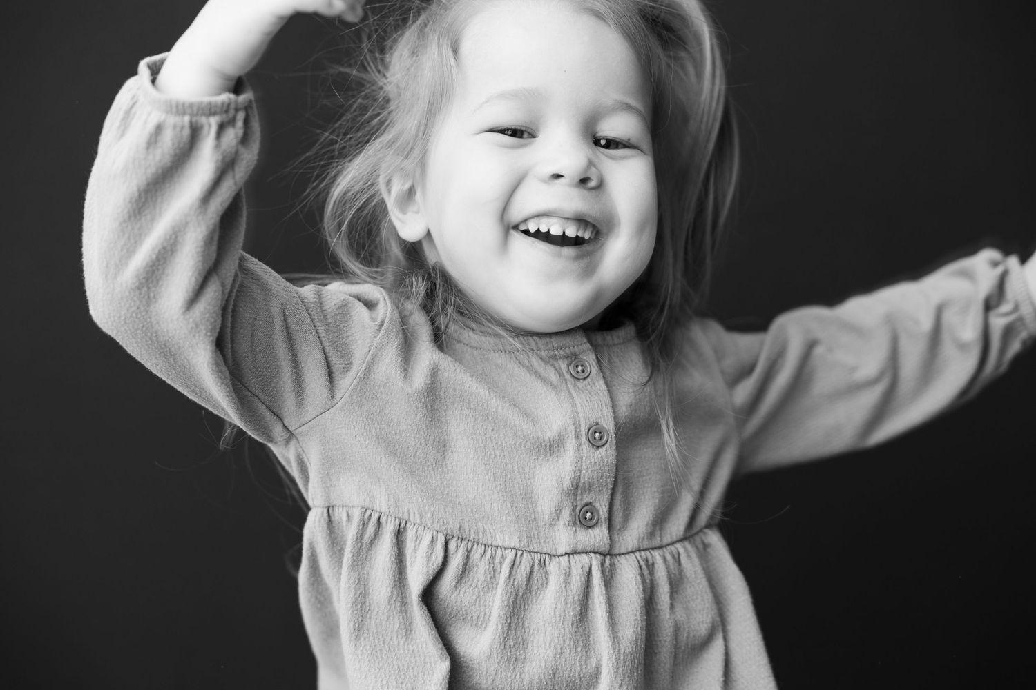 Black and white photo sequence showing a young child in motion wearing a light colored top and displaying joyful expressions.