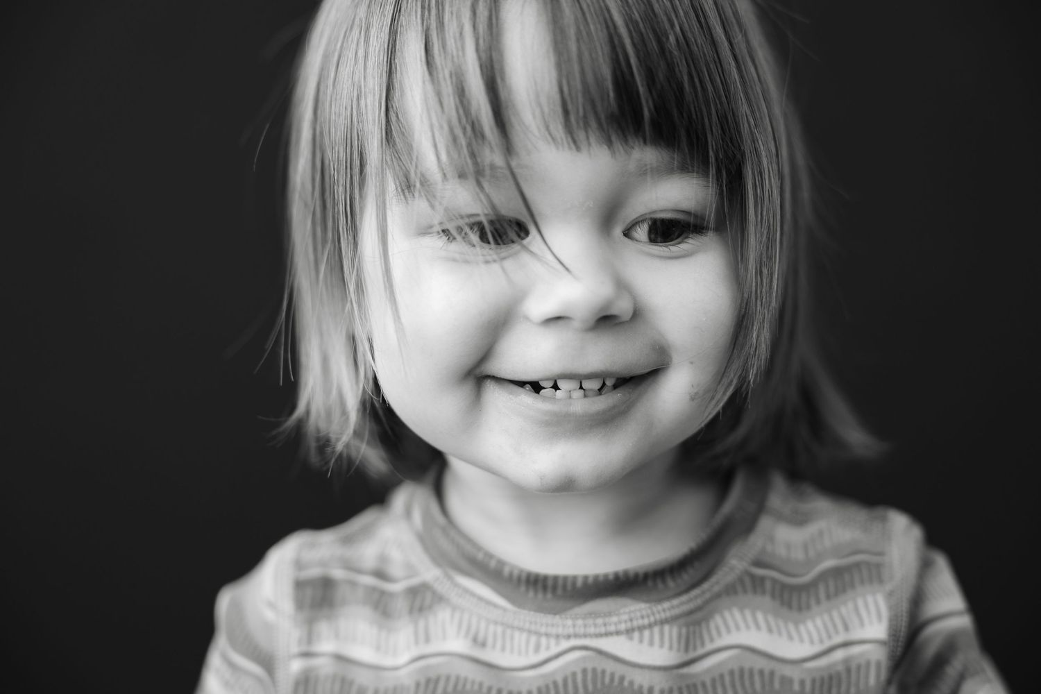 A series of black and white portraits showing a child smiling and expressing various playful emotions.