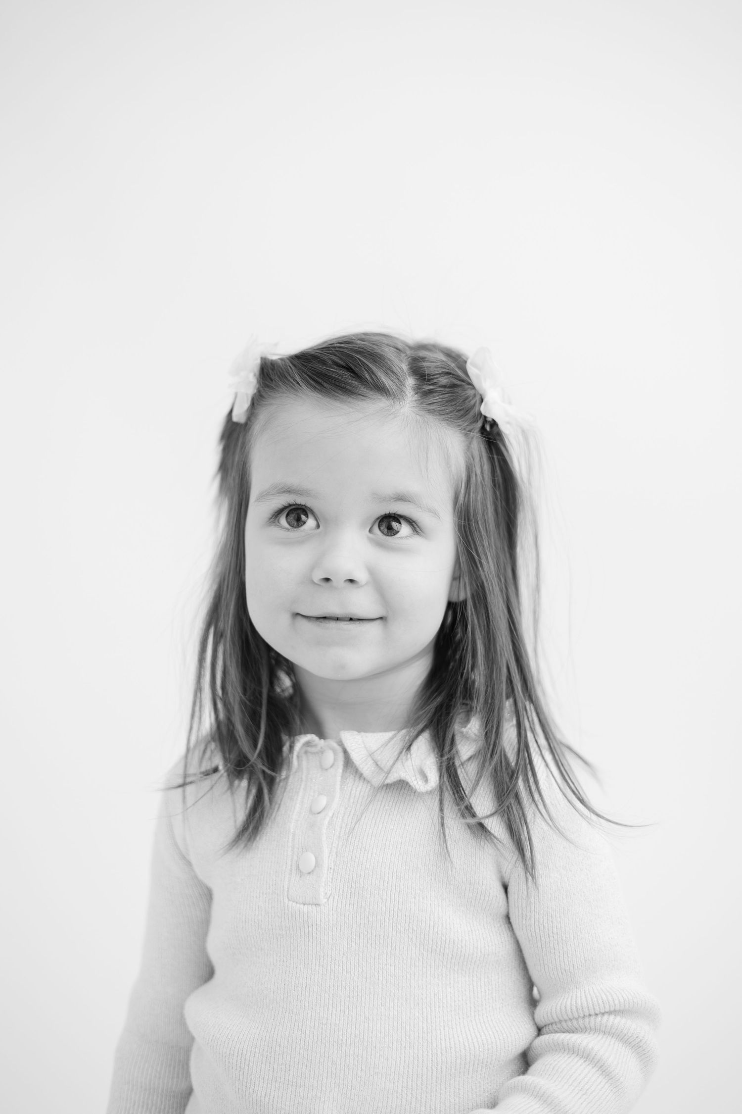 A series of four black and white portraits of a young child in a white collared shirt looking upward with wonder.