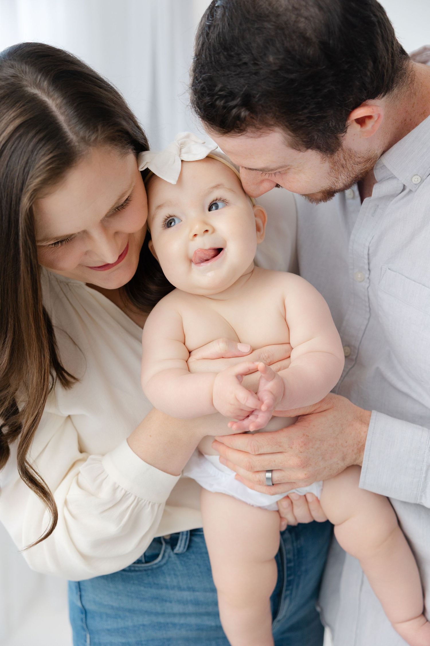 Parents lovingly hold and interact with their baby in a series of tender moments against a white background.