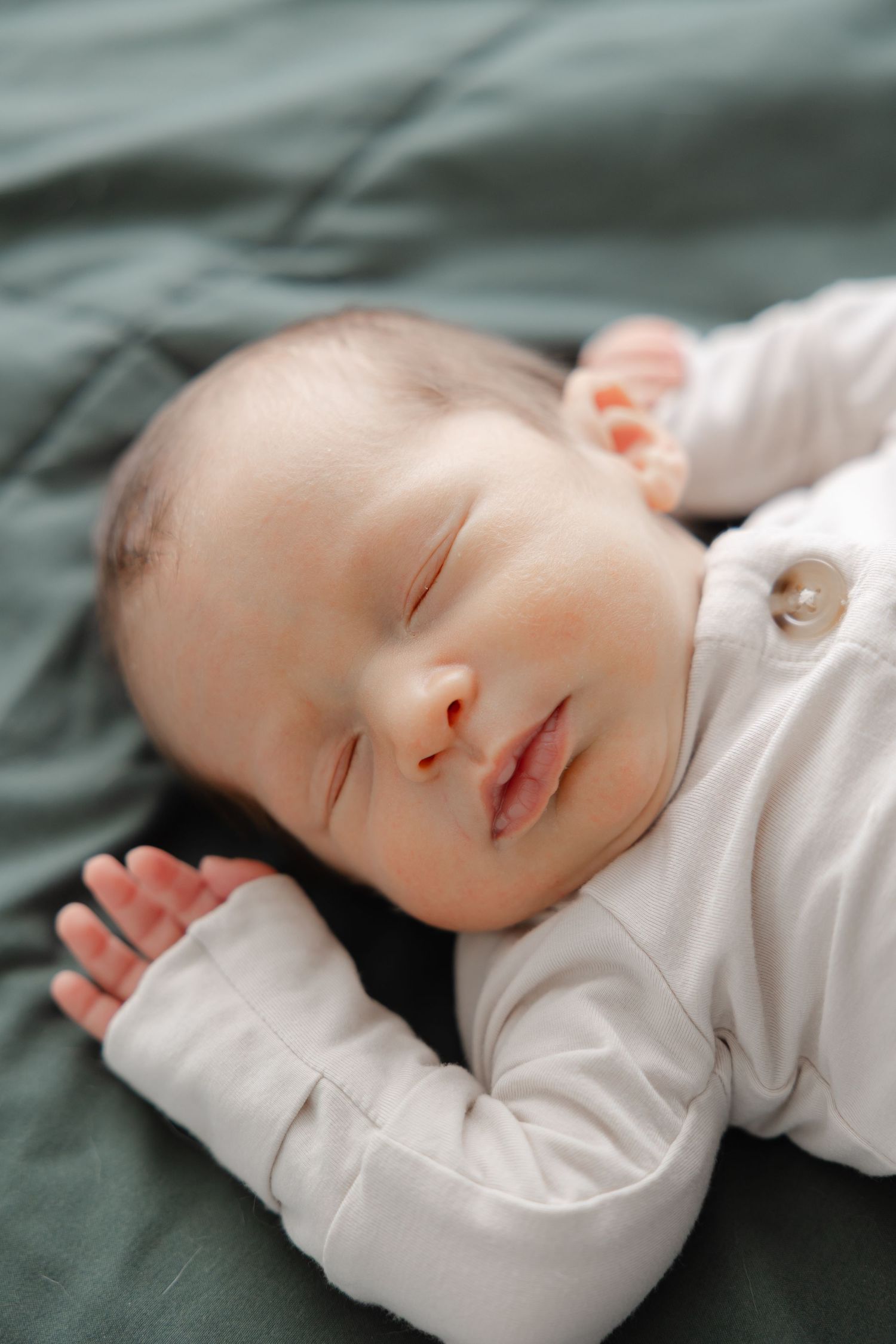 An image of a peaceful sleeping newborn baby on a bed taken by Heather Wall with Hello Indy Photography.