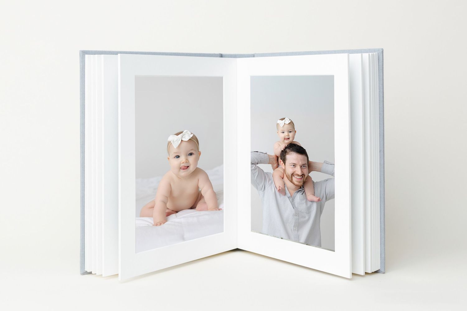 White photo album with multiple pages spread out in an accordion style layout displaying soft monochromatic images.