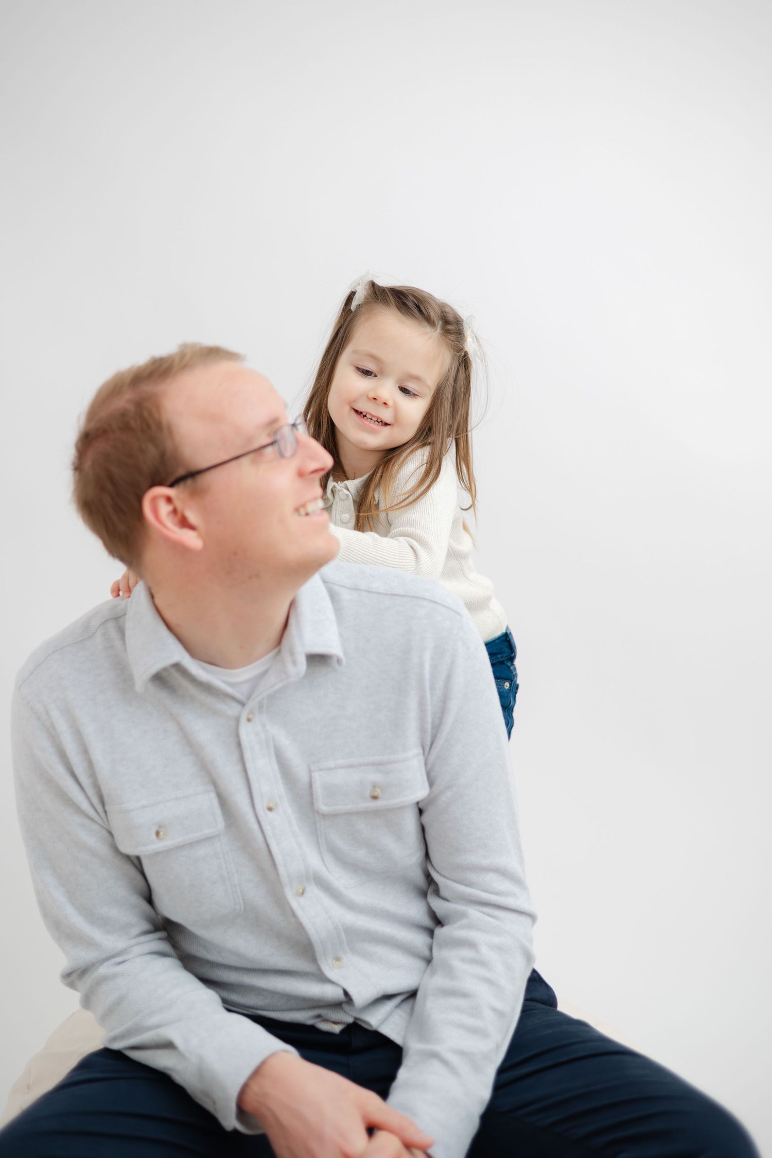 A heartwarming moment between parent and child sharing laughter against a white studio backdrop.
