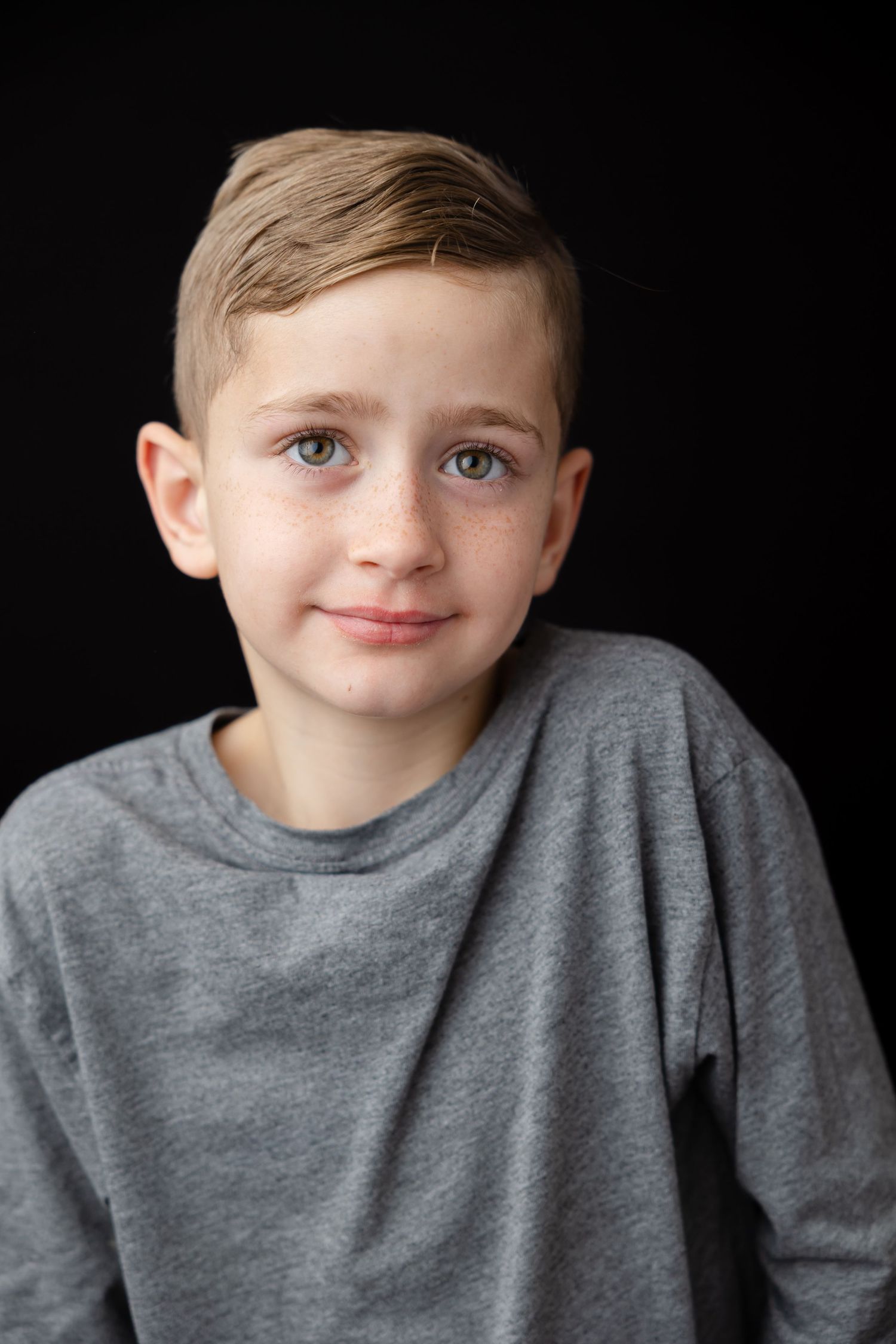 Portrait series on black background showing expressions in grey sweater spanning from reserved to joyful.