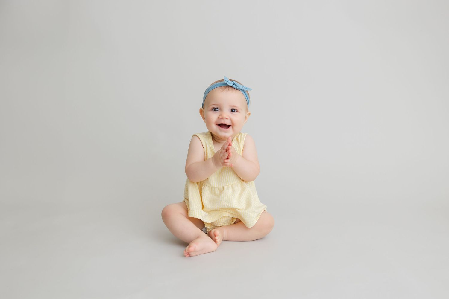 A baby wearing a yellow outfit sits and smiles on a light gray background in a progression of shots.