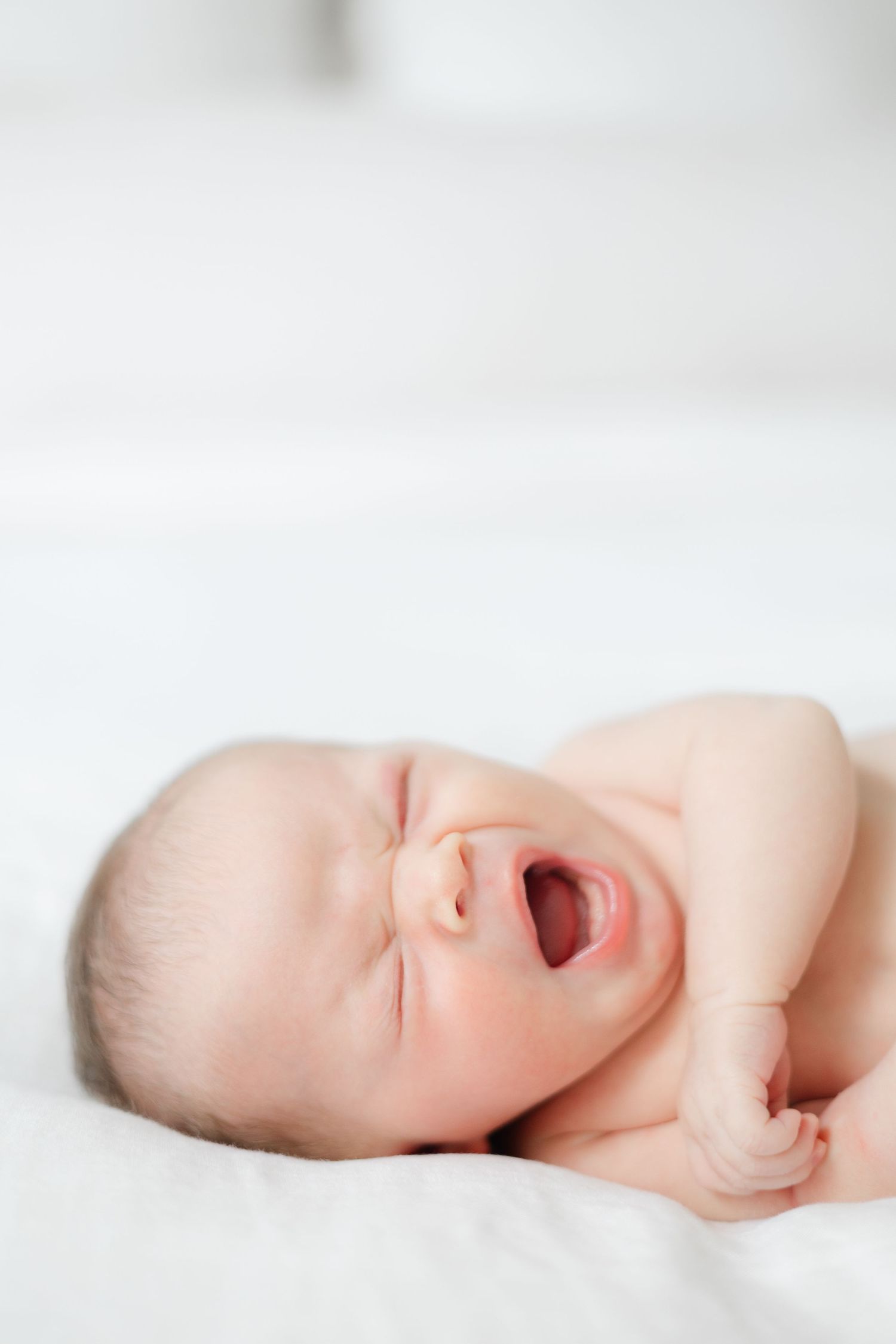 A serene sleeping newborn baby rests peacefully on soft white bedding.