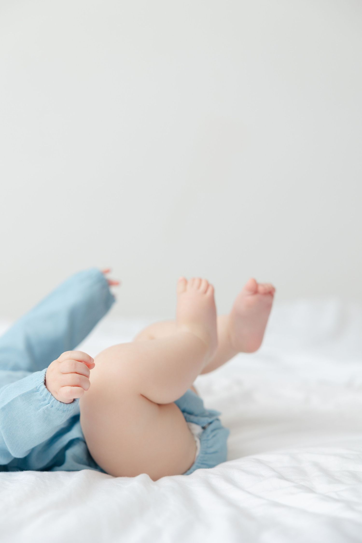 Close-up view of tiny baby feet on white bedding showing four different angles in a collage format.