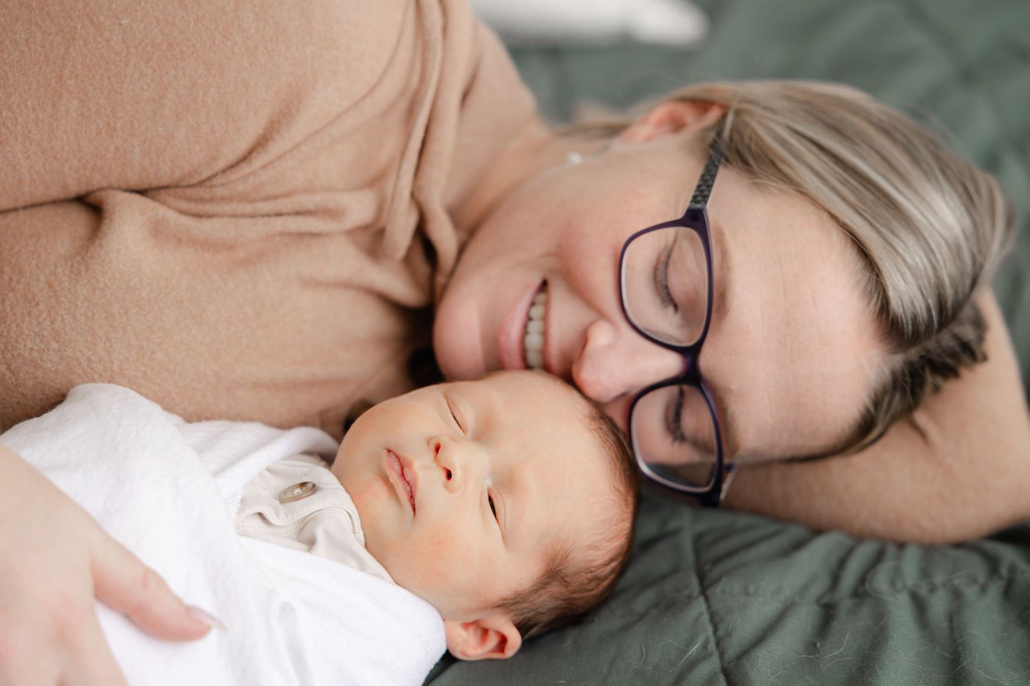 Close up lifestyle photo of someone peacefully sleeping on a light colored bed with cozy bedding.