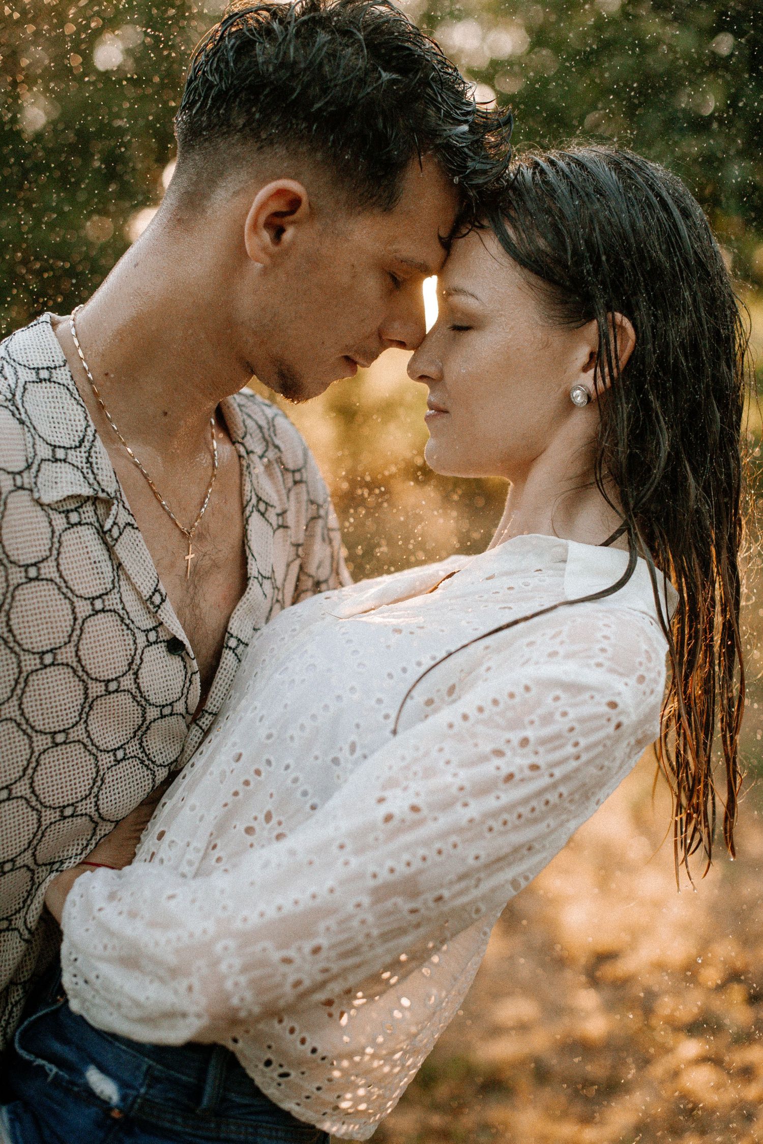 Romantic moment captured in warm golden light with water droplets.