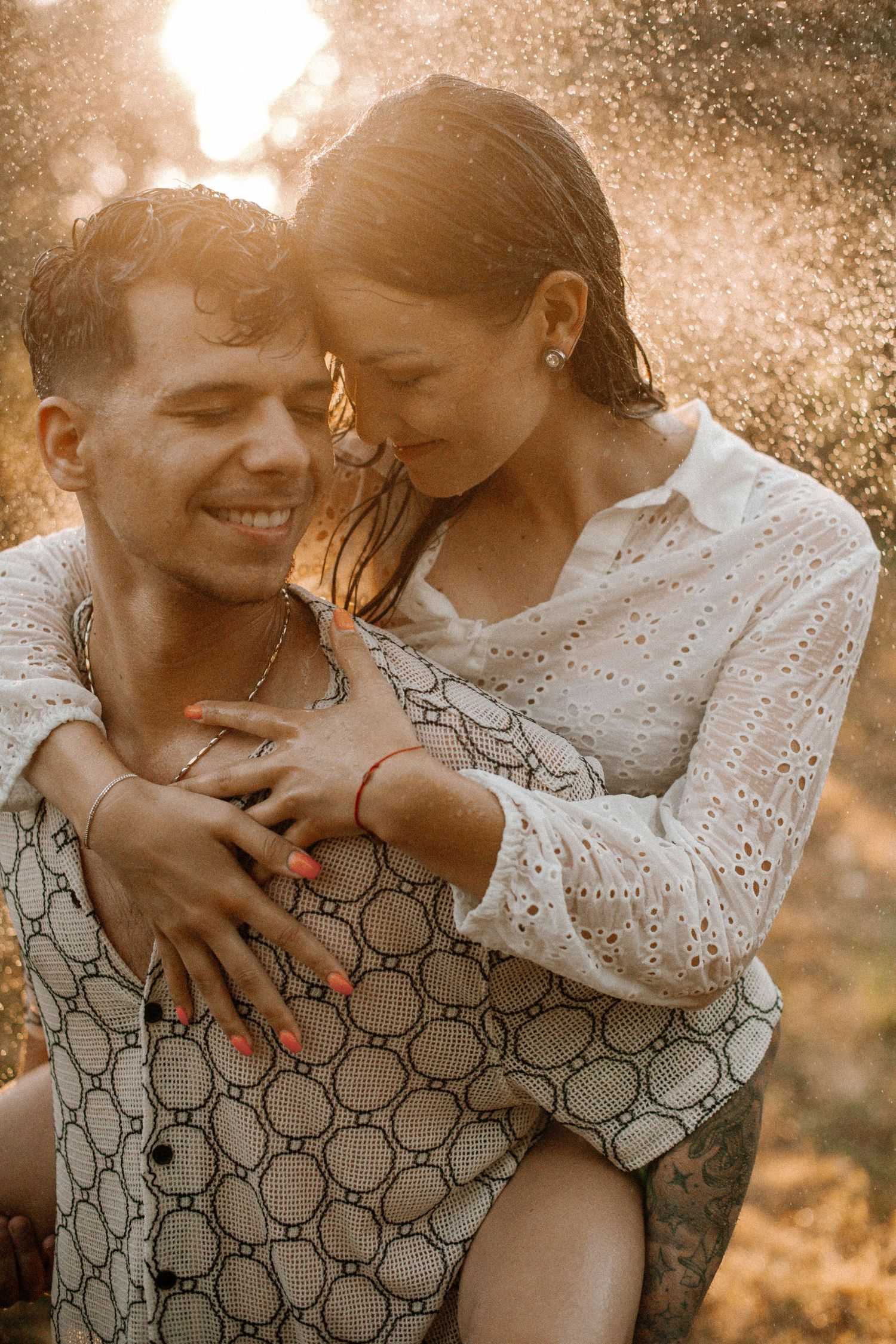 Tender embrace captured in warm golden light with water droplets.