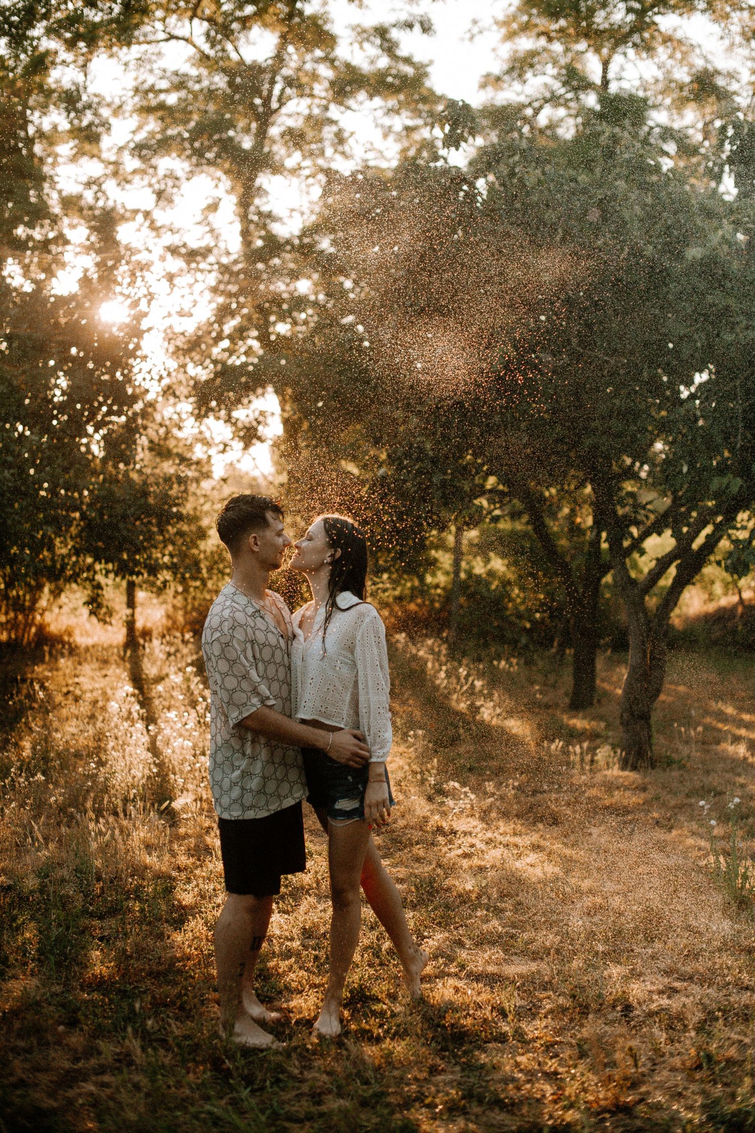 Couple embracing in magical golden hour light with water spray.