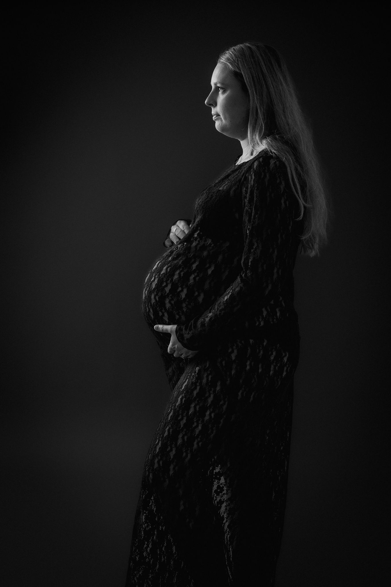 Svartvit bild på gravid kvinna som fotograferas i en fotostudio i mullsjo / jonkoping. Hon har svart klänning.