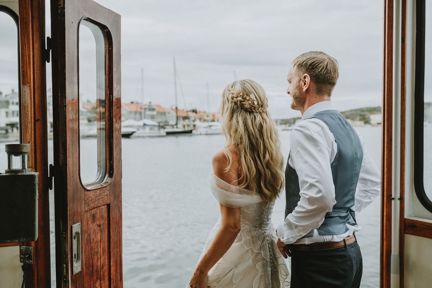 Brudpar står i fören på en båt och tittar ut över Marstrandsön.