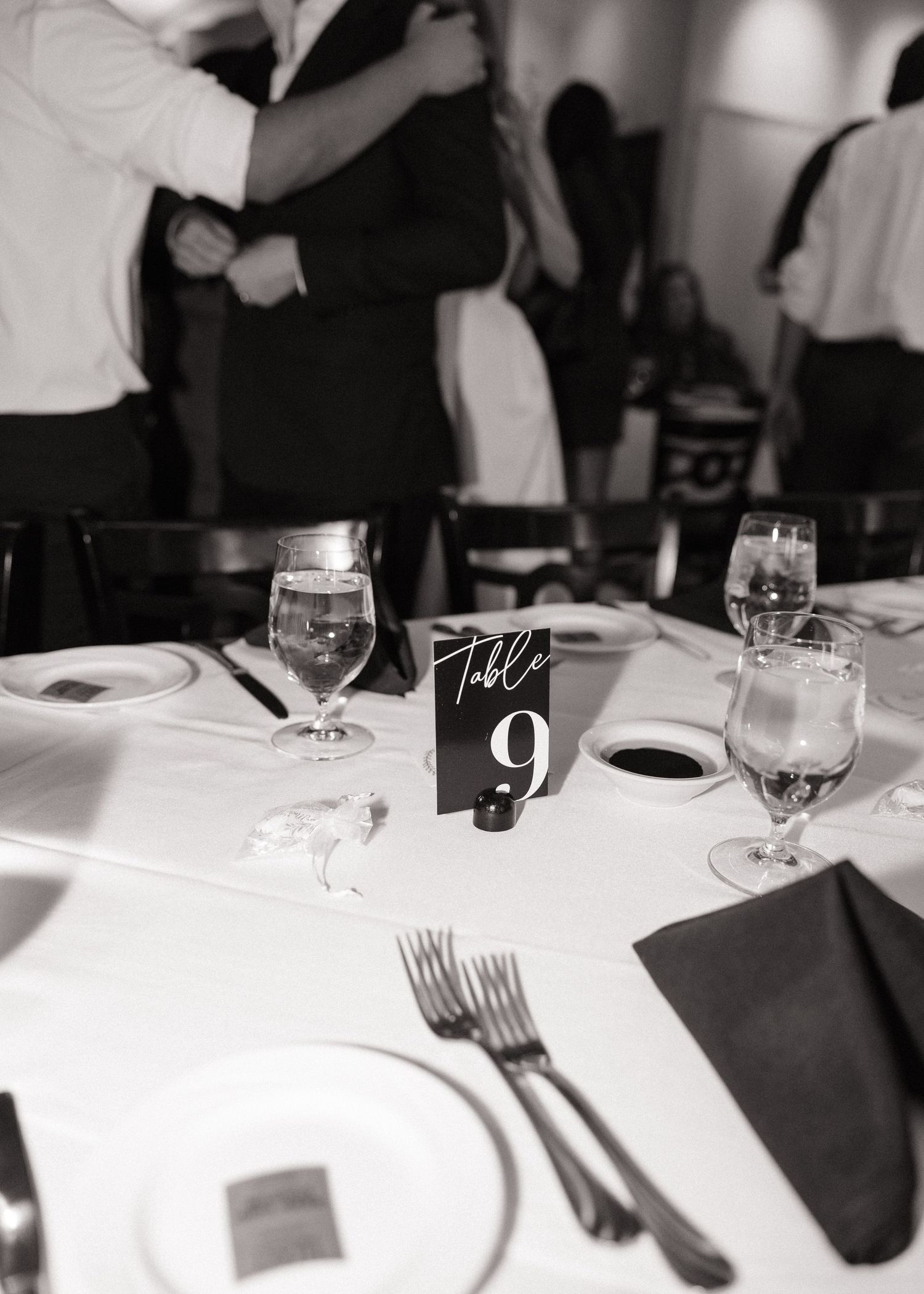 Wedding reception table setting with wine glasses, plates, and table number nine at formal dinner event.